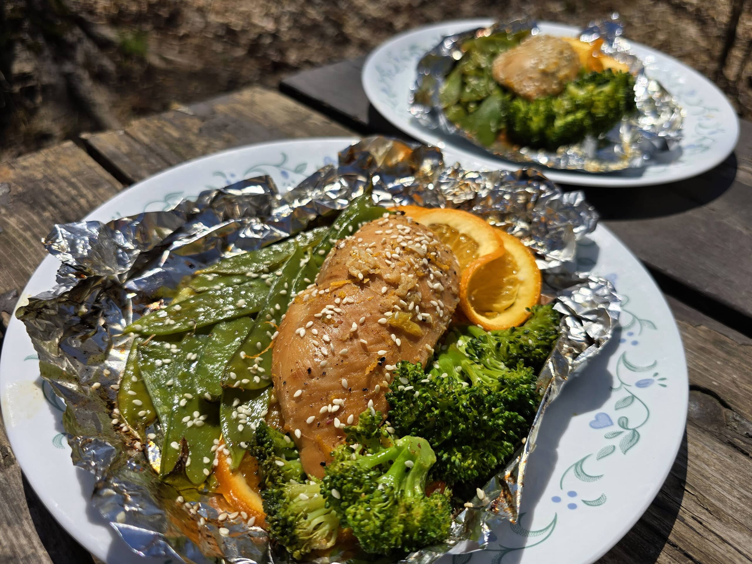 2 portions of ginger orange chicken foil packet meals, with broccoli and peas.