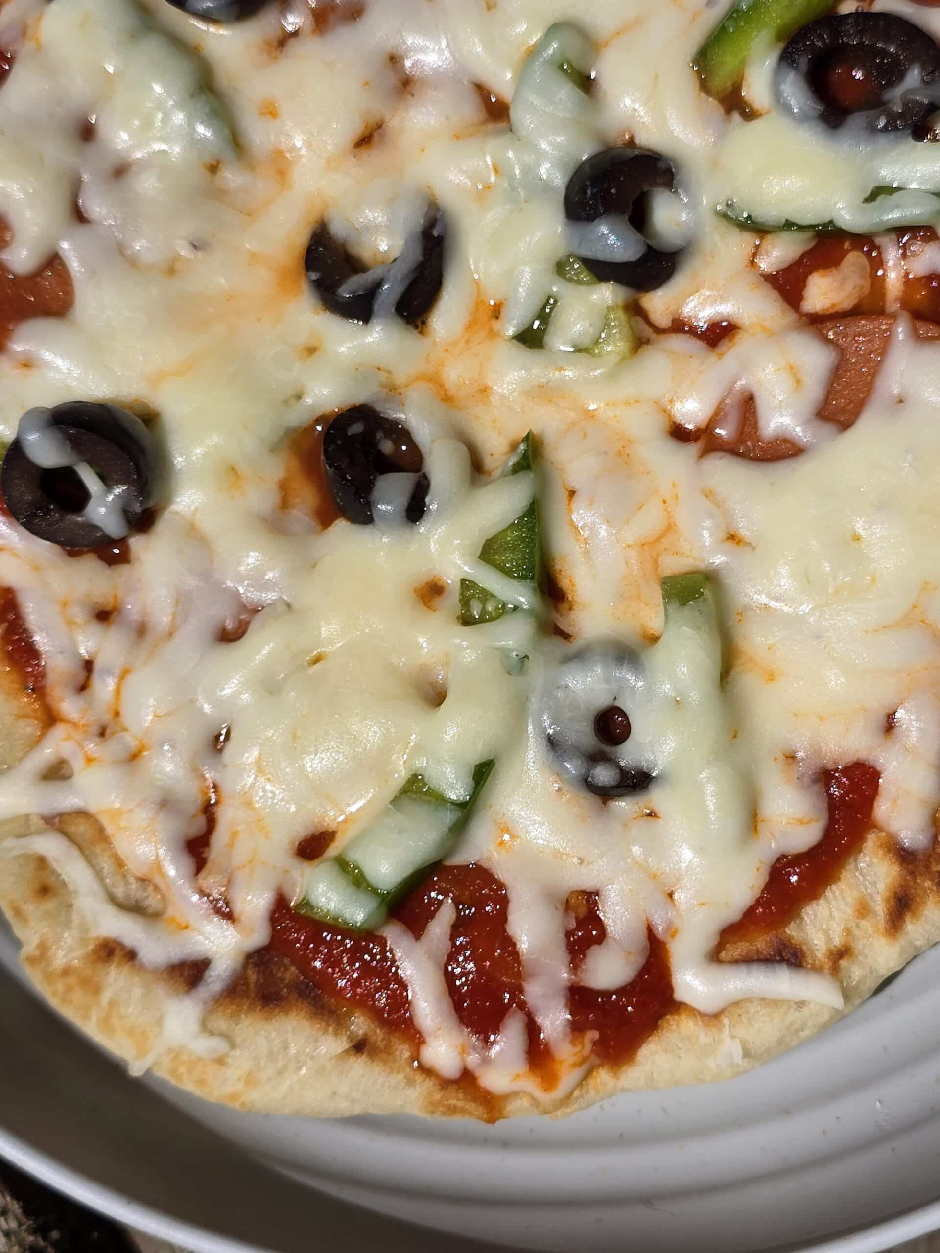 An individual camp fire pizza on a plate.