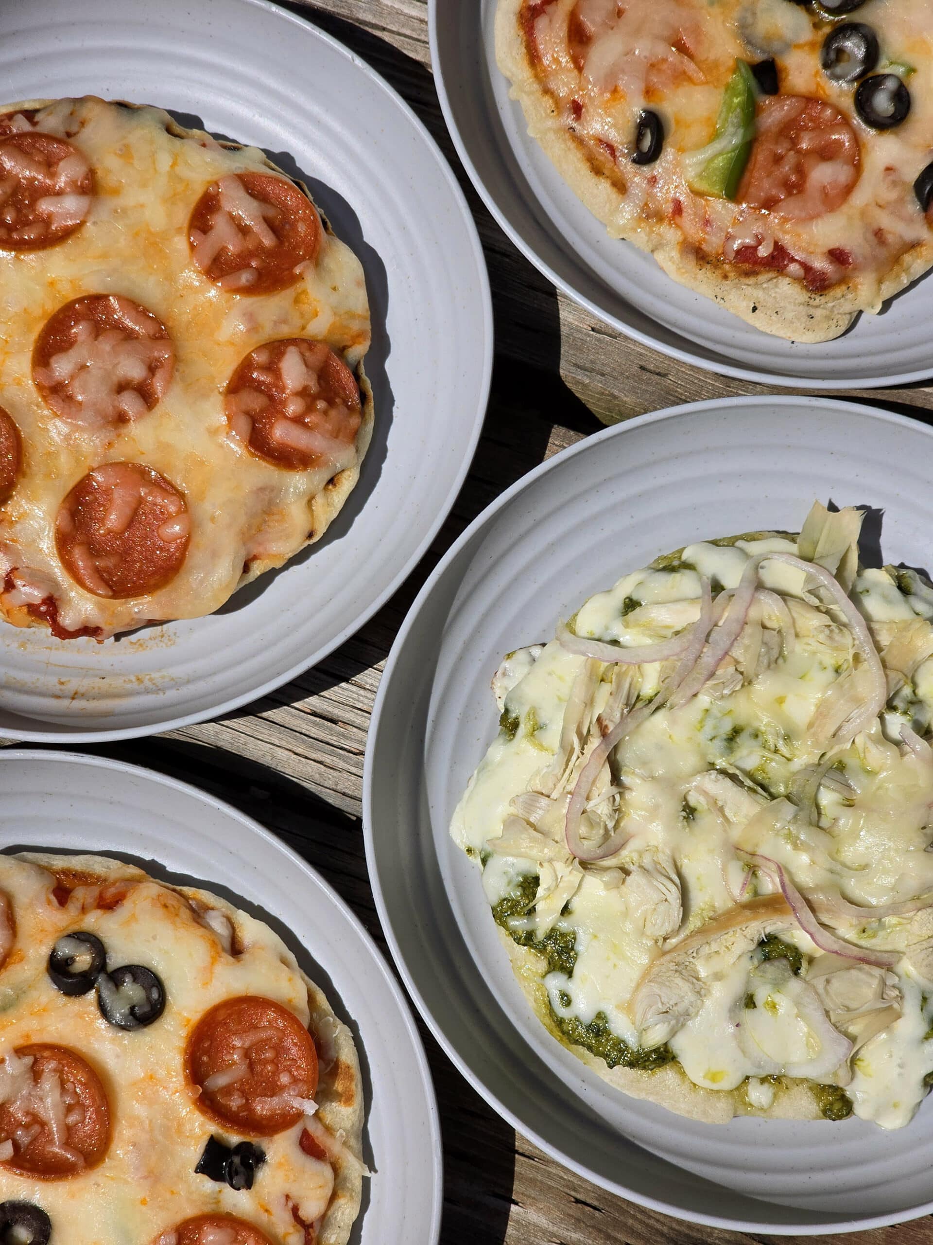 Four individual campfire pizza pies, each on a plate.