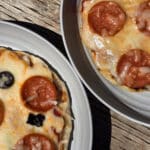 Two individual campfire pizzas, each on a plate.