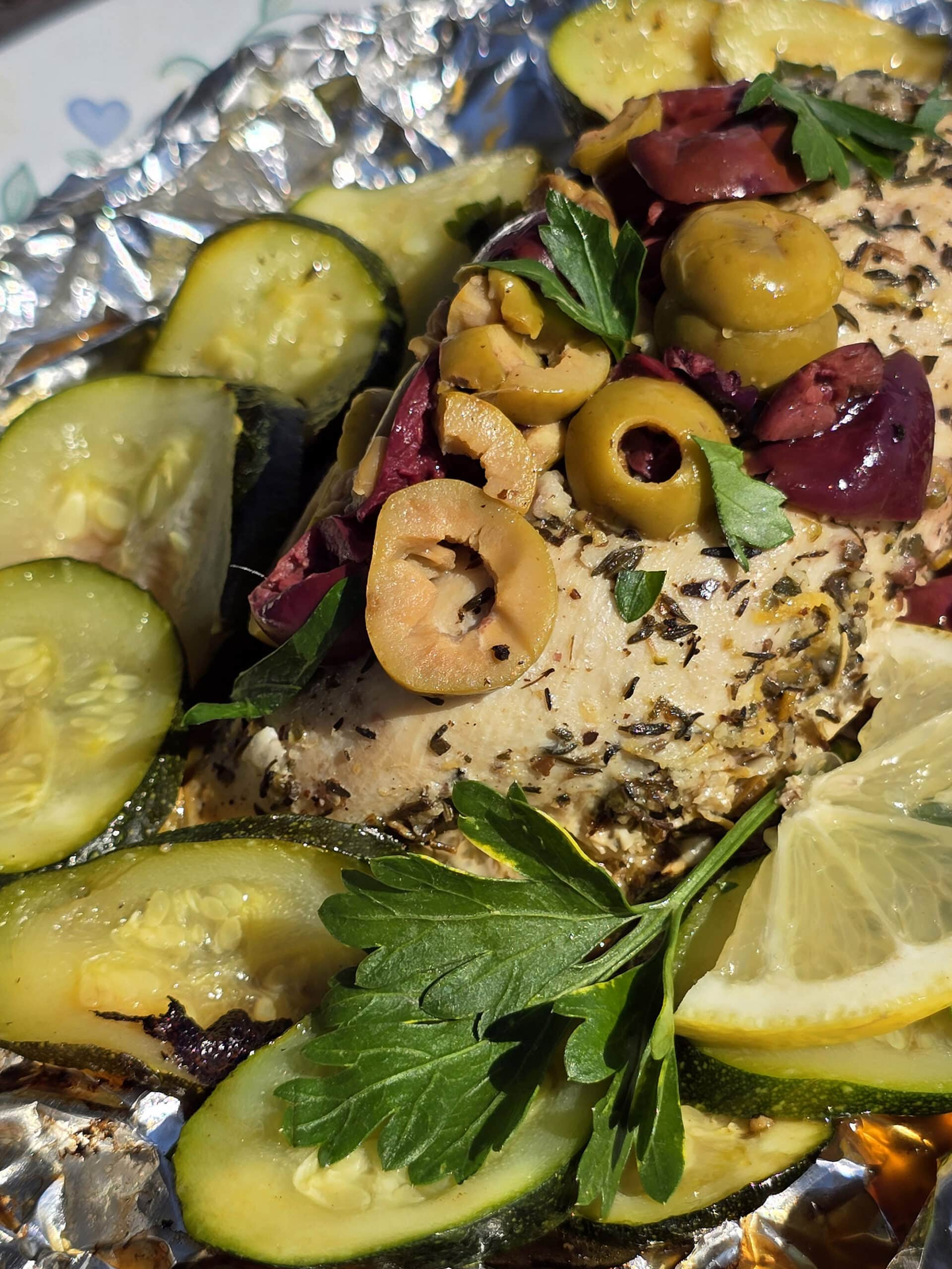 Souvlaki chicken foil packets with lemon slices, grilled zucchini, parsley, and olives.