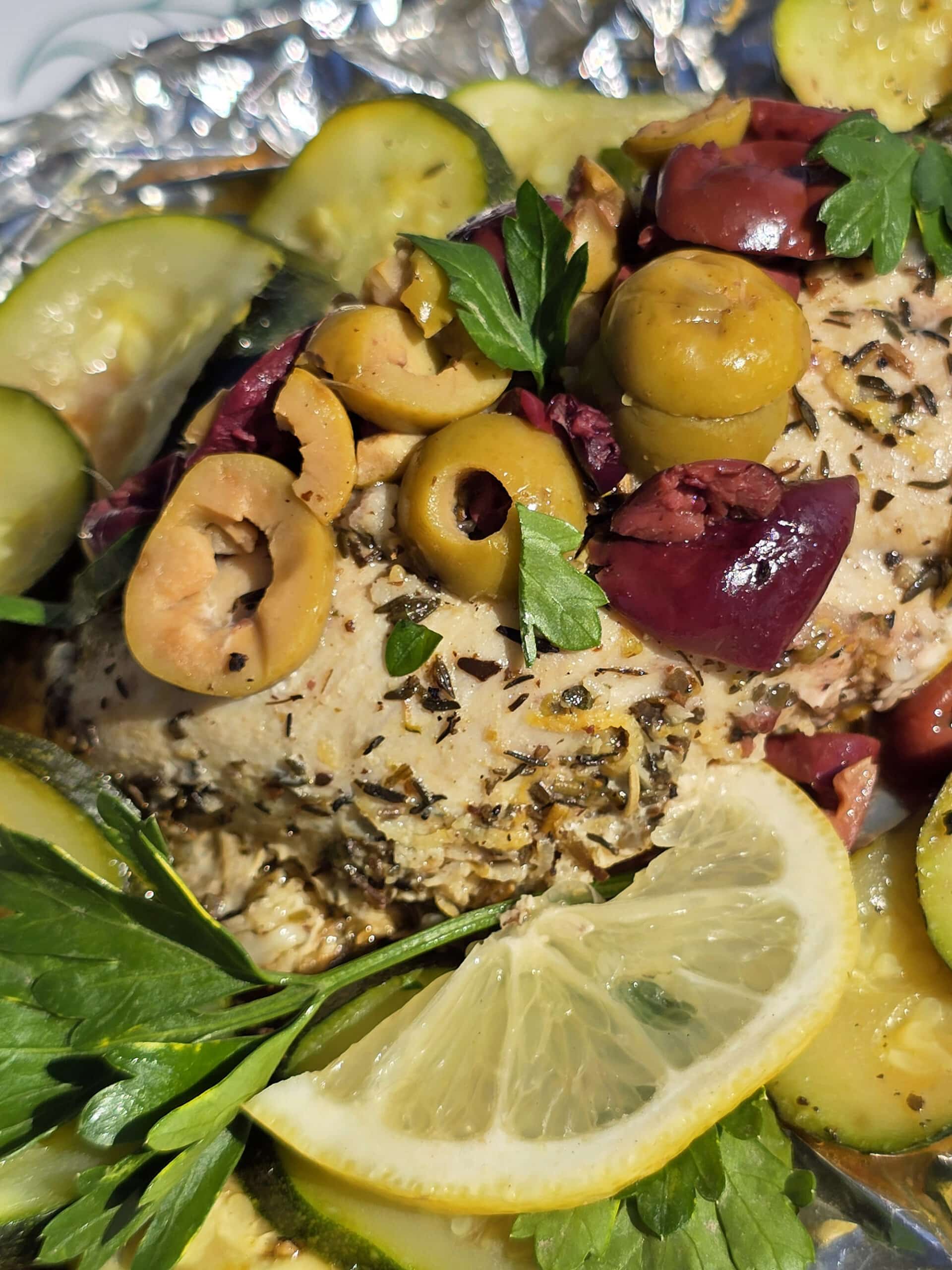 Souvlaki chicken foil packets with lemon slices, grilled zucchini, parsley, and olives.