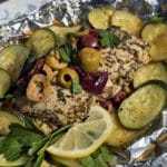 Souvlaki chicken foil packets with lemon slices, grilled zucchini, parsley, and olives.