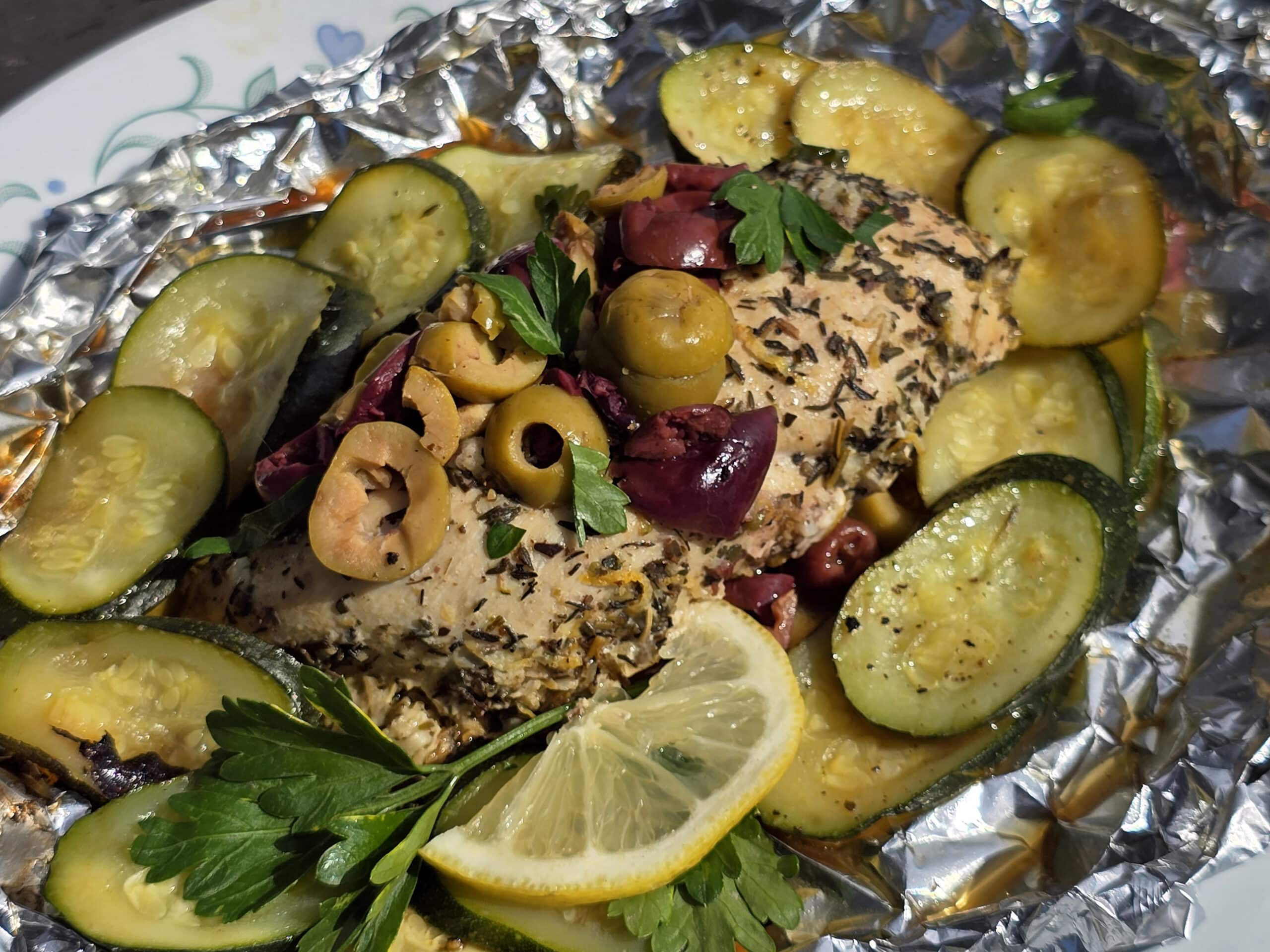 Souvlaki chicken foil packets with lemon slices, grilled zucchini, parsley, and olives.