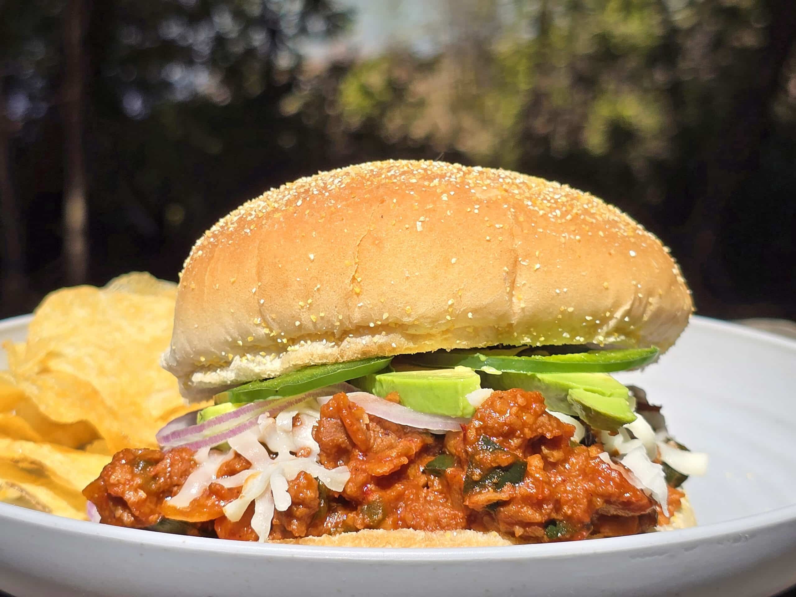 A Mexican sloppy Jose sandwich, with Monterrey Jack, sliced jalapenos, and avocado, on a plate.