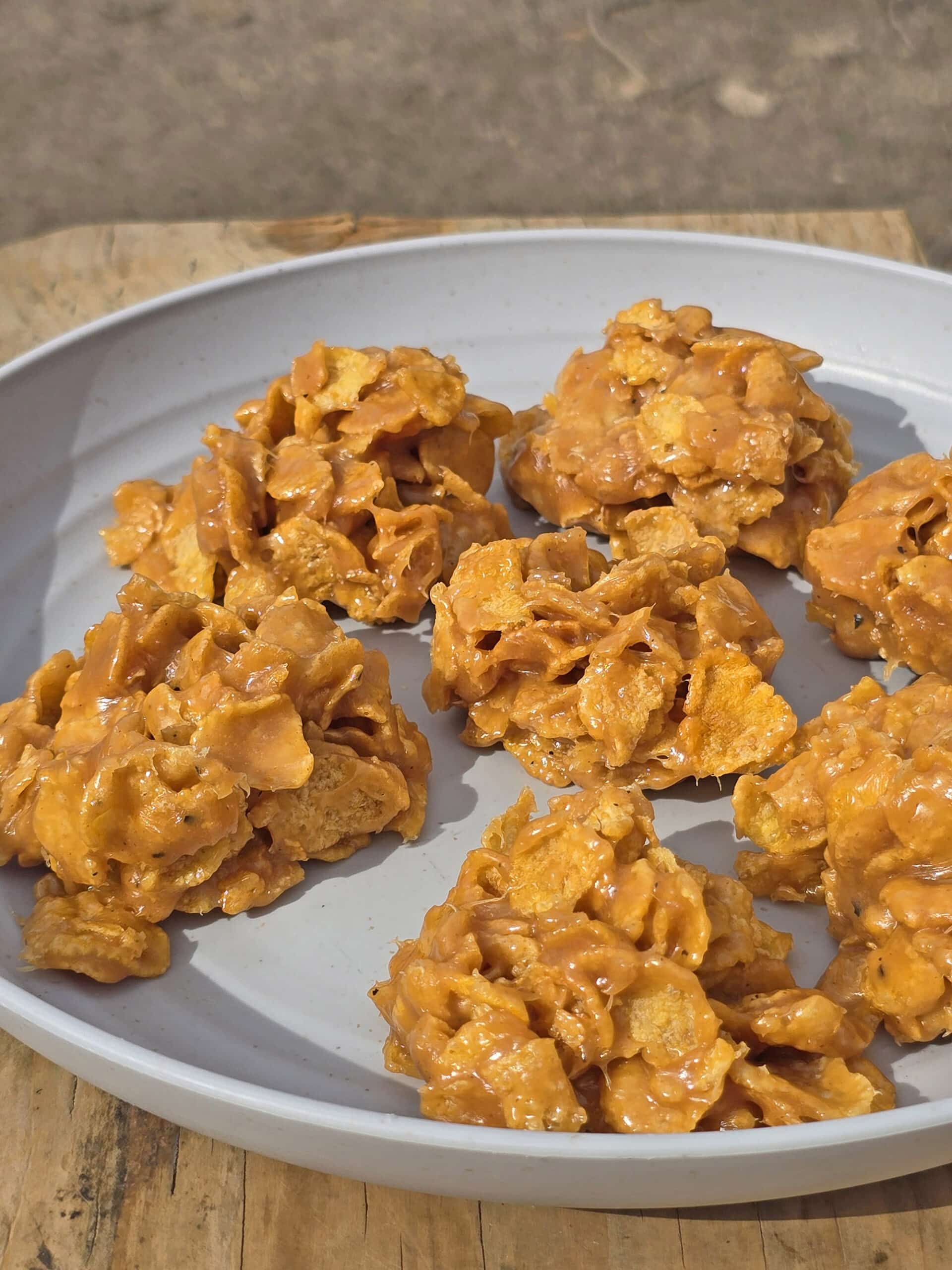 A plate of no bake cornflake cookies on a picnic table.