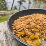 A skillet of apple crisp on a picnic table.