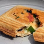 A pizza pudgy pie on a plate, filled with mozzarella, green peppers, pepperoni, and black olives.