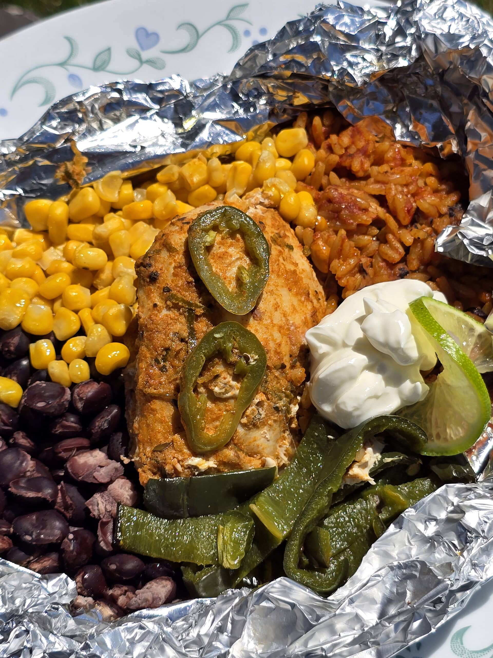 A Southwestern Chicken foil packet, with Southwest marinated chicken, black beans, corn, Mexican rice, and poblano peppers.