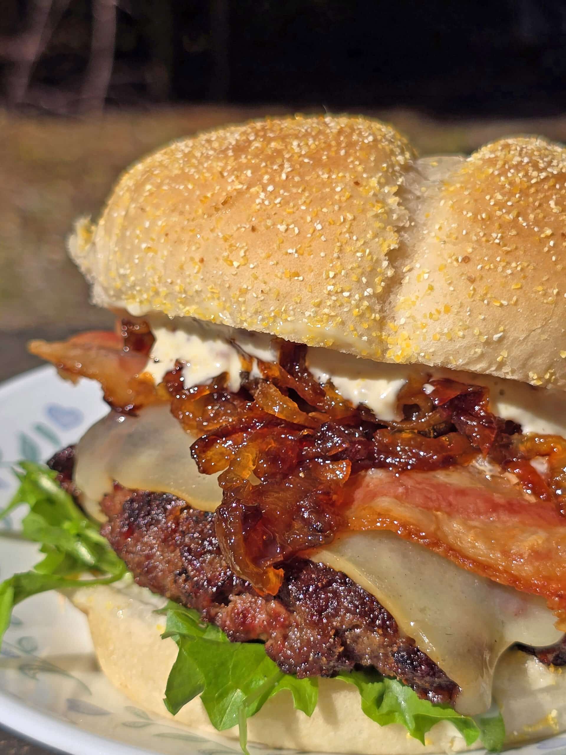 A venison burger with smoked cheddar, bacon, dijonnaise, and whiskey caramelized onions.