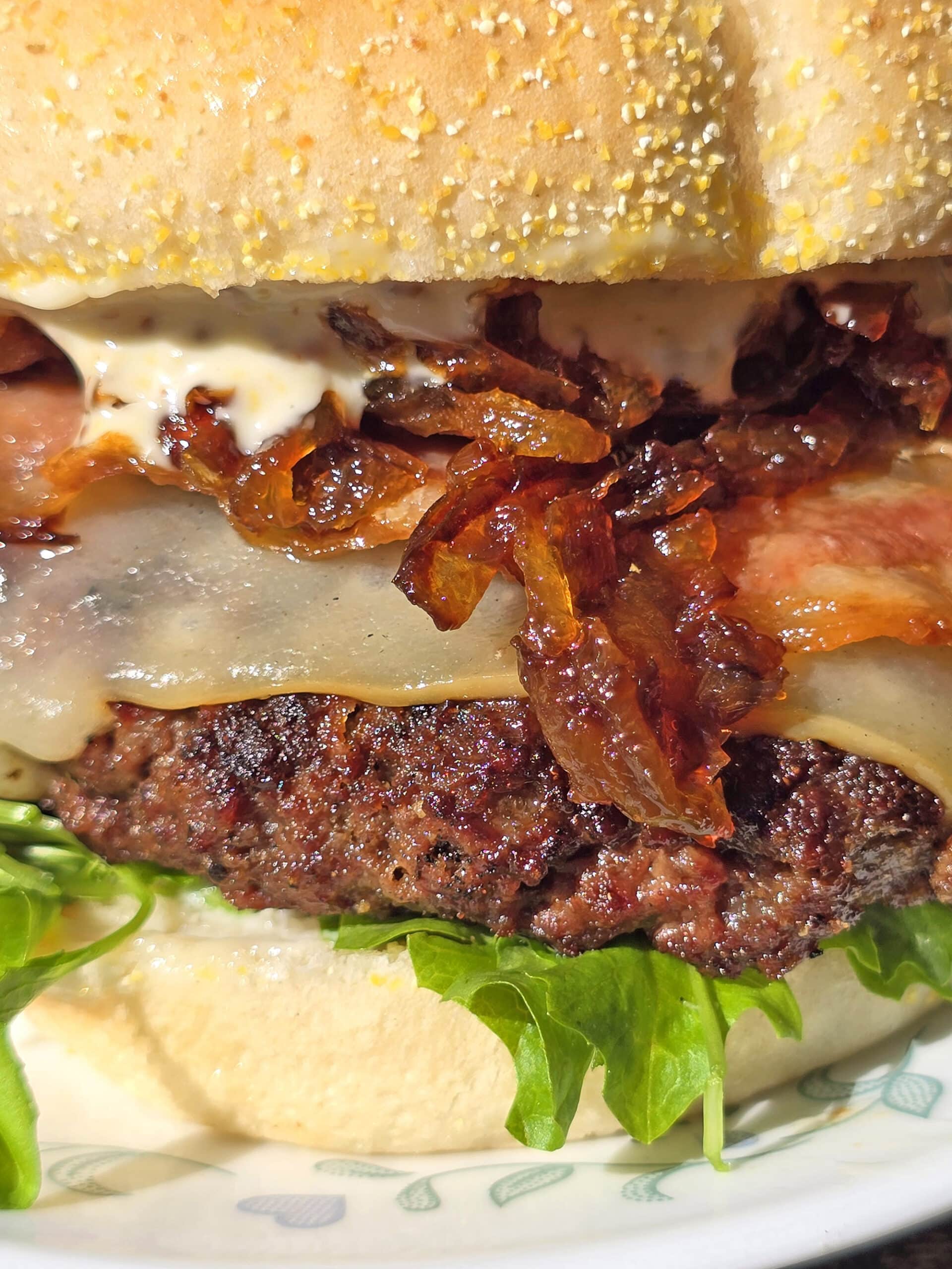 A venison burger with smoked cheddar, bacon, dijonnaise, and whiskey glazed onions.