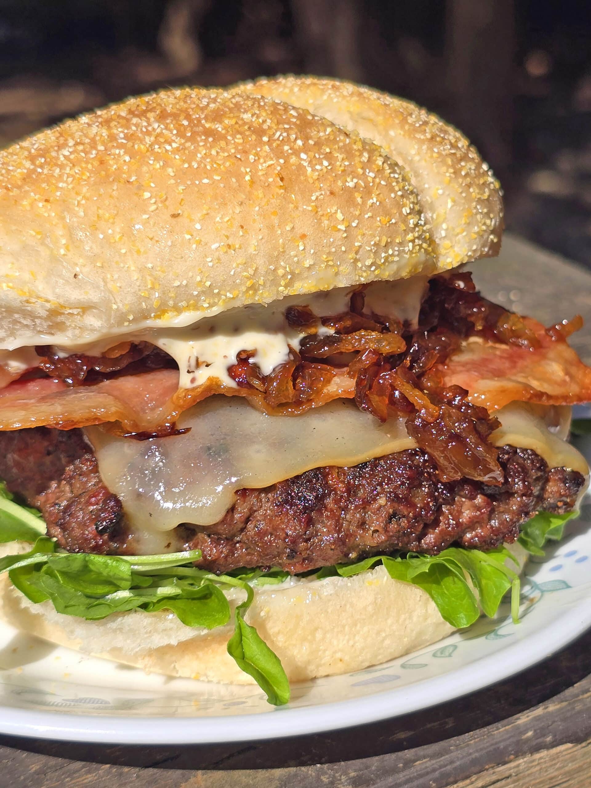 A venison burger with smoked cheddar, bacon, dijonnaise, and whiskey caramelized onions.