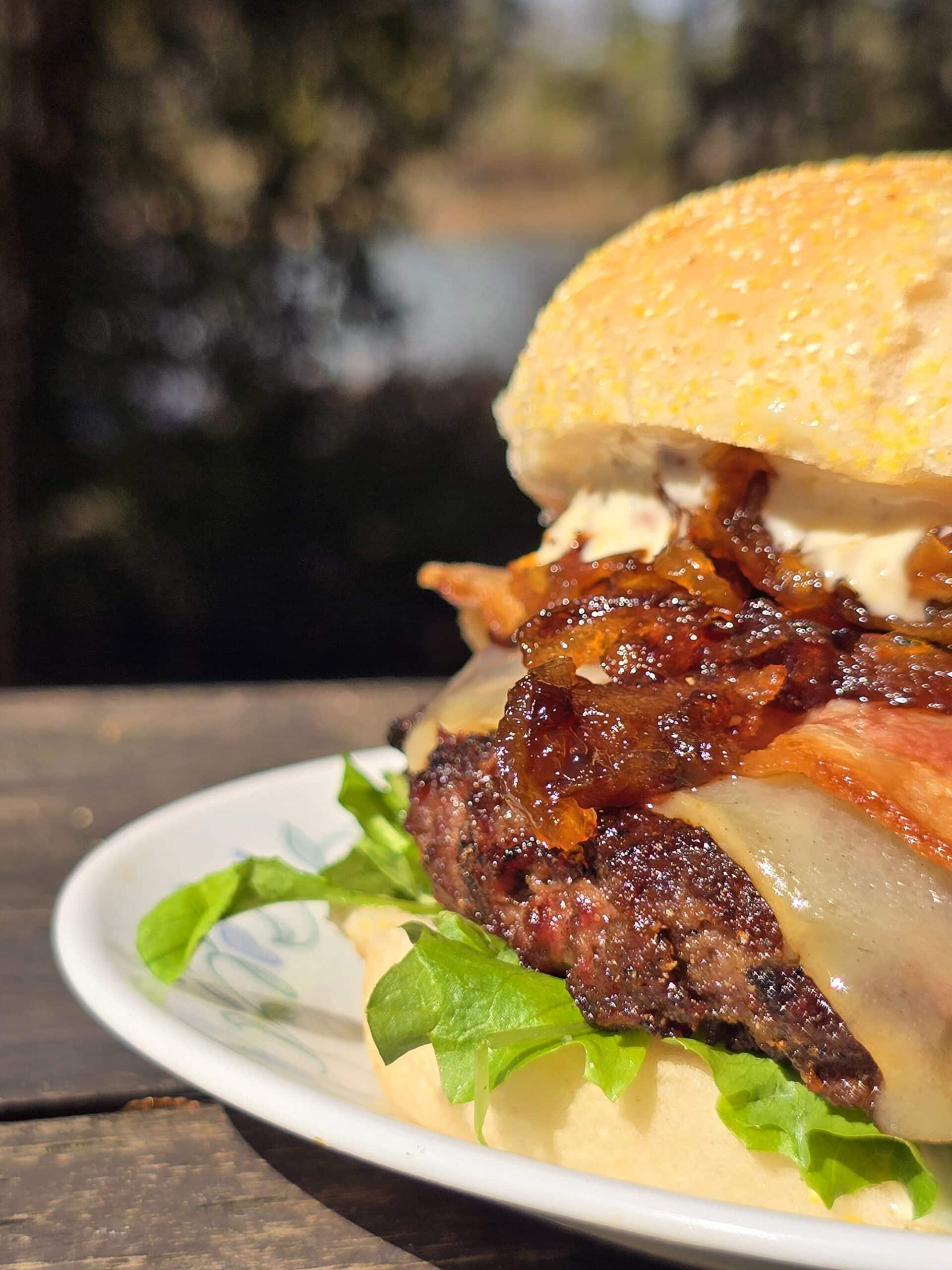 A venison burger with smoked cheddar, bacon, dijonnaise, and whiskey glazed onions.