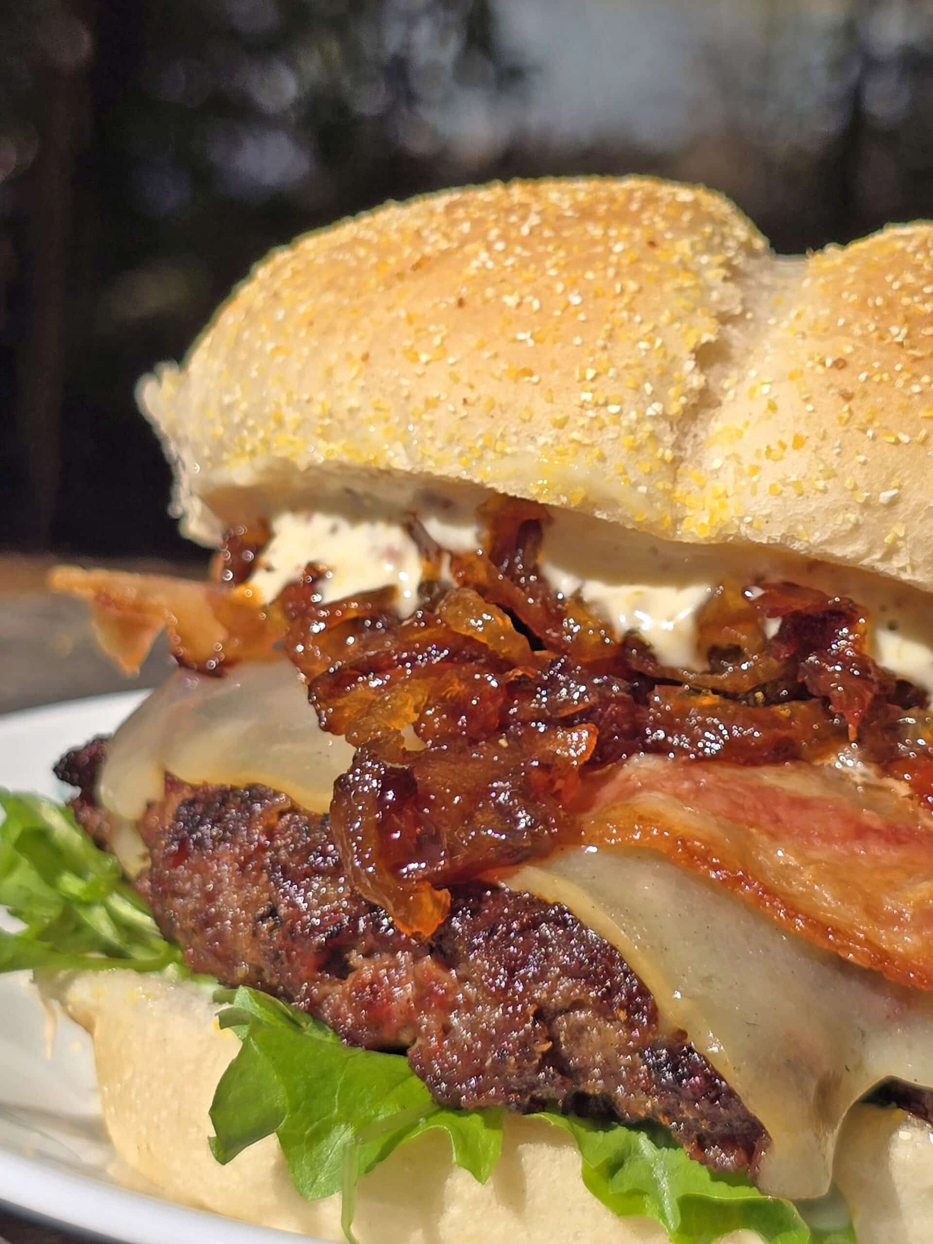 A venison burger with smoked cheddar, bacon, dijonnaise, and whiskey caramelized onions.