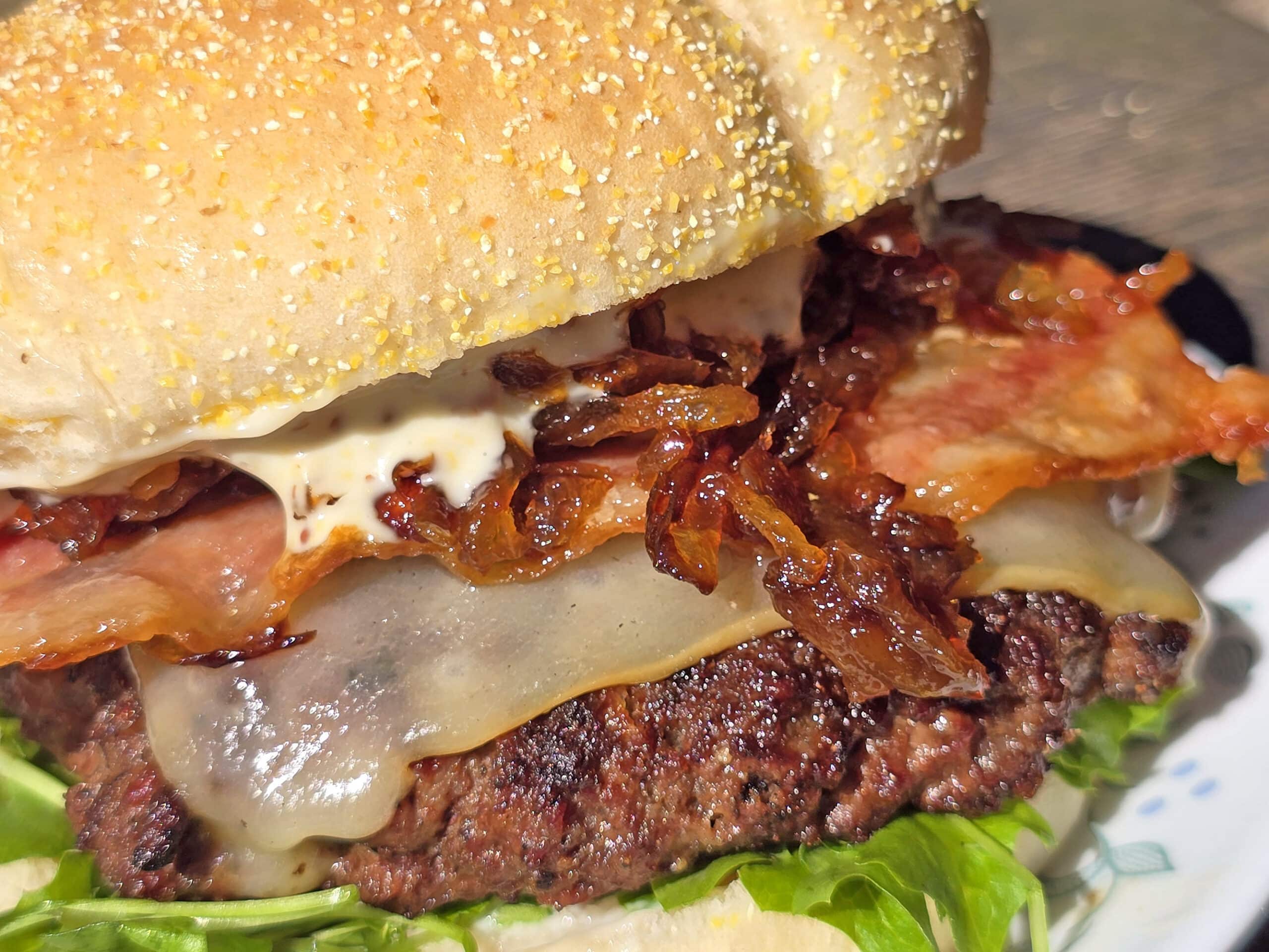 A venison burger with smoked cheddar, bacon, dijonnaise, and whiskey glazed onions.