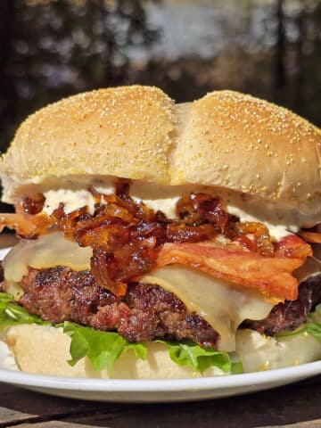 A venison burger with smoked cheddar, bacon, dijonnaise, and whiskey caramelized onions.