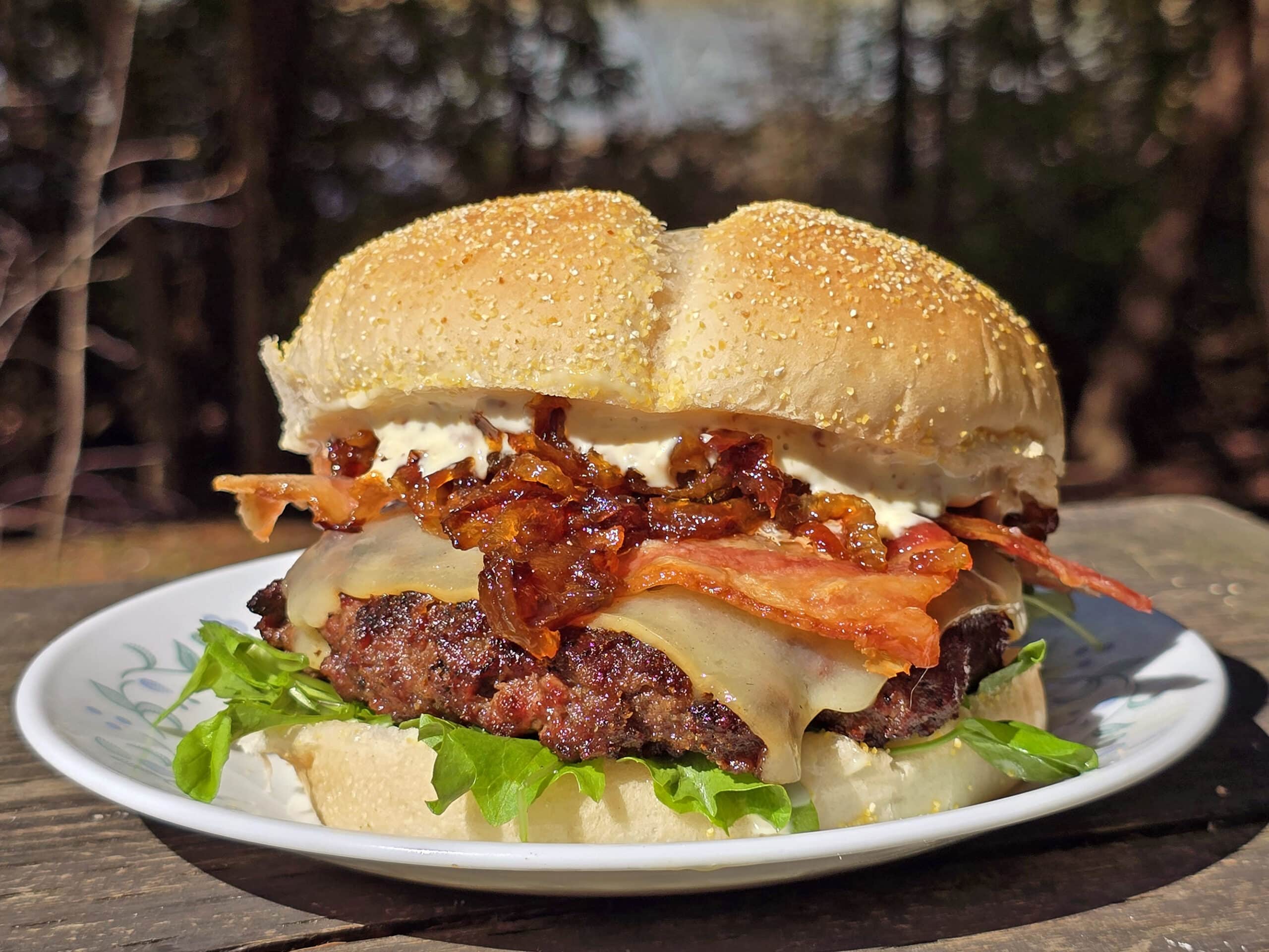 A venison burger with smoked cheddar, bacon, dijonnaise, and whiskey caramelized onions.