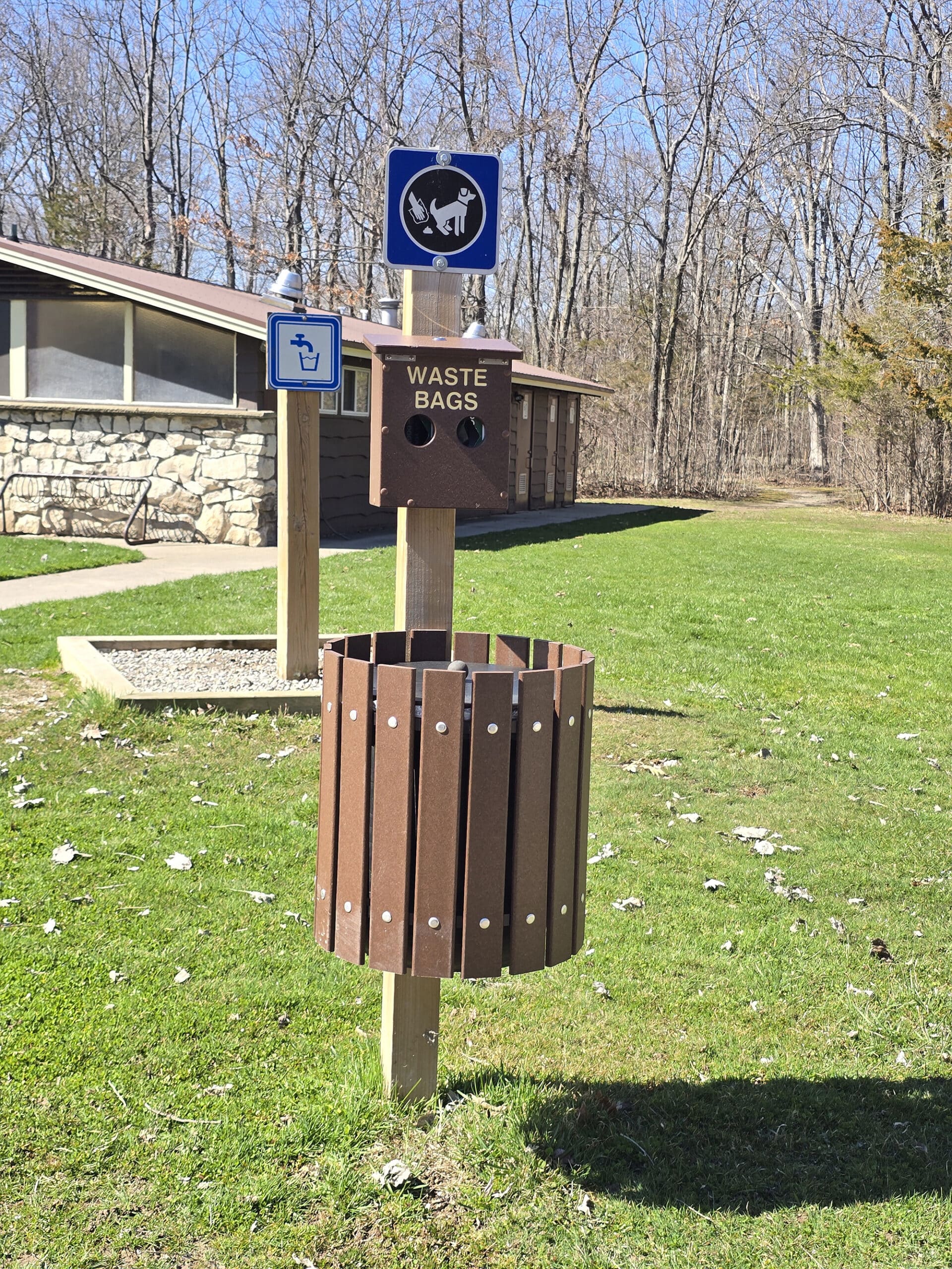 A garbage bin with attached poop baggie dispenser.
