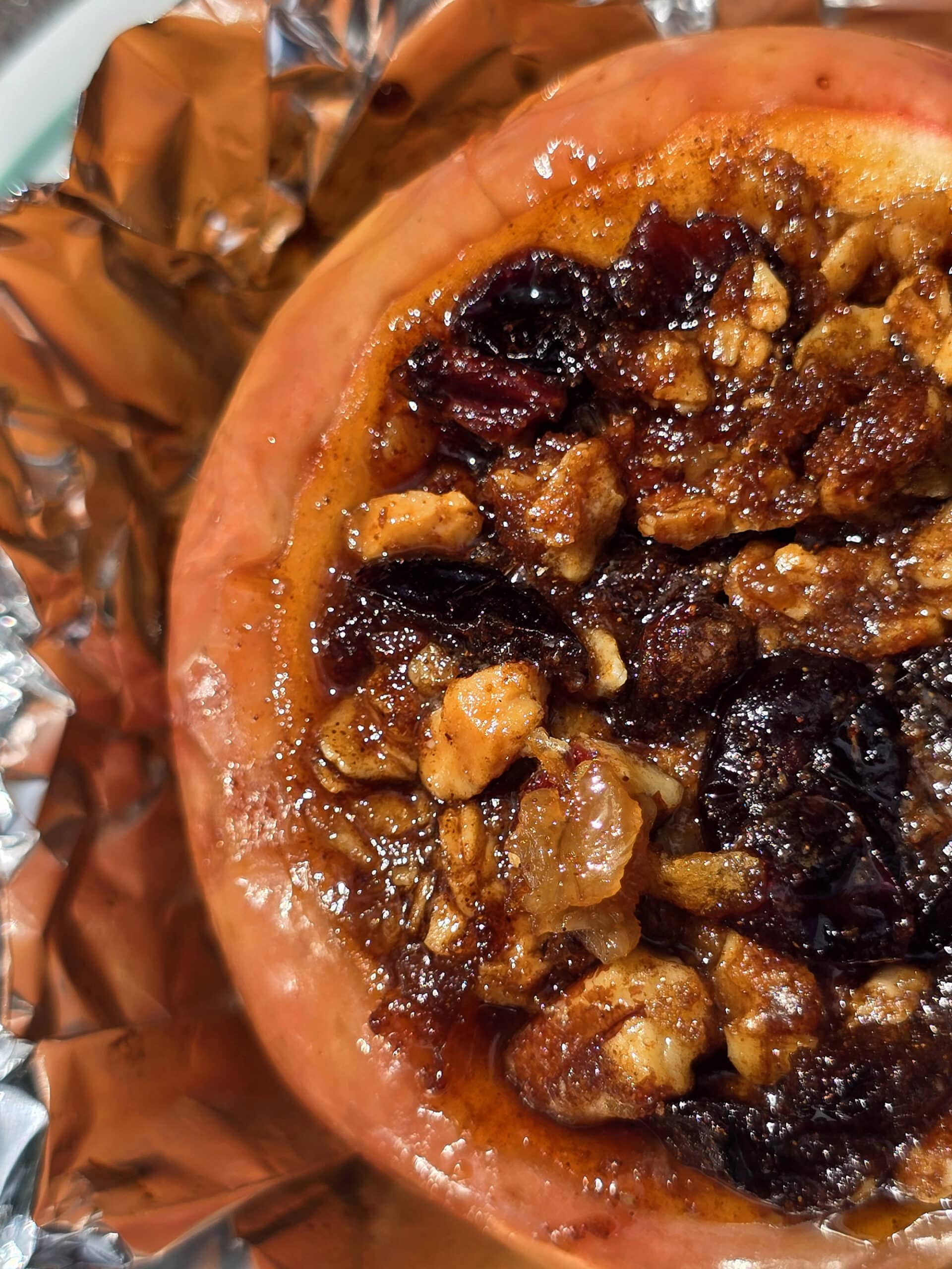 A large campfire baked apple in foil, stuffed with granola, raisins, brown sugar, nuts, and cinnamon.