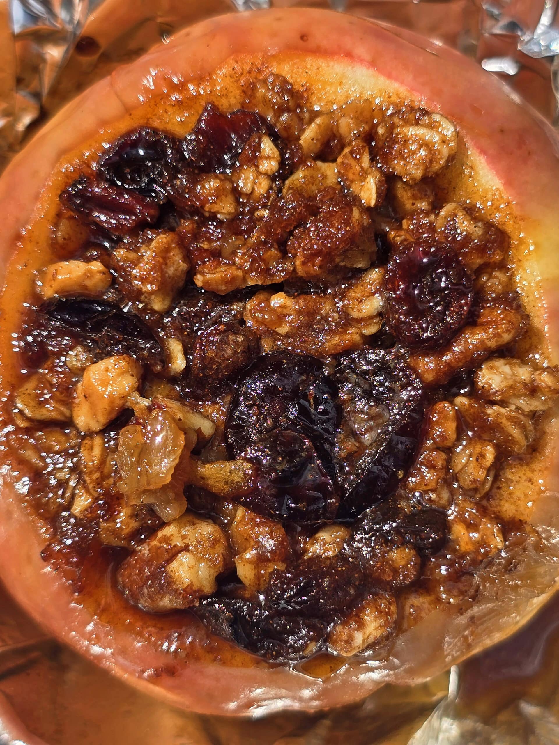 A large campfire baked apple in foil, stuffed with granola, raisins, brown sugar, nuts, and cinnamon.