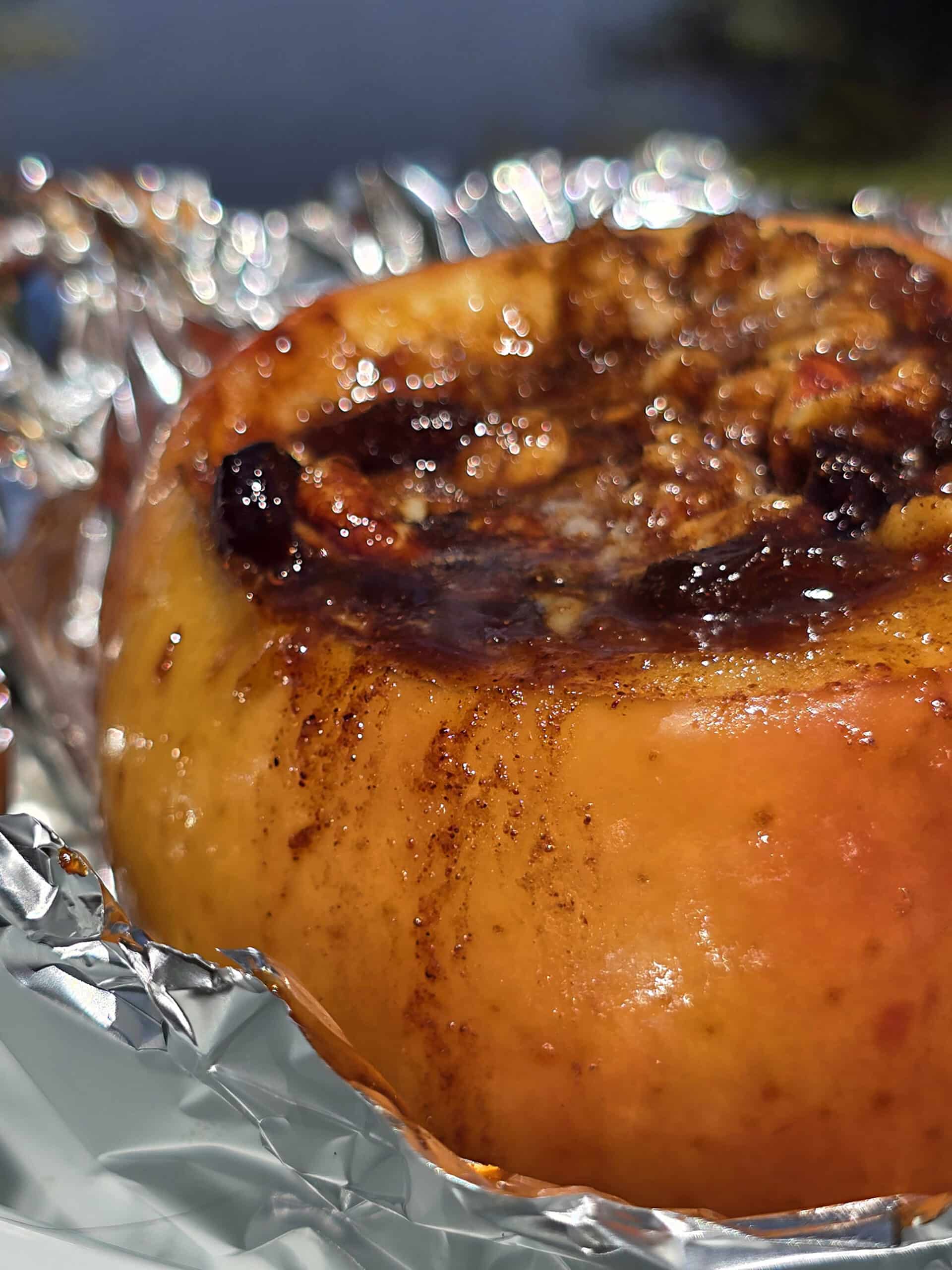 A large campfire baked apple in foil, stuffed with granola, raisins, brown sugar, nuts, and cinnamon.