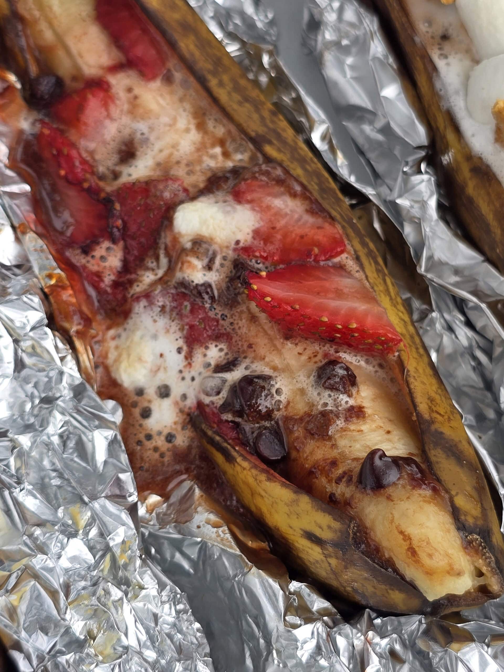 A grilled banana boat stuffed with marshmallows, strawberries and chocolate chips.