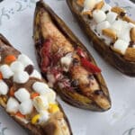 3 grilled banana boats. One is stuffed with reeses pieces peanut butter cups and marshmallows, another with marshmallows, strawberries and chocolate chips, and the final one with marshmallows, chocolate chips, and golden grahams cereal.
