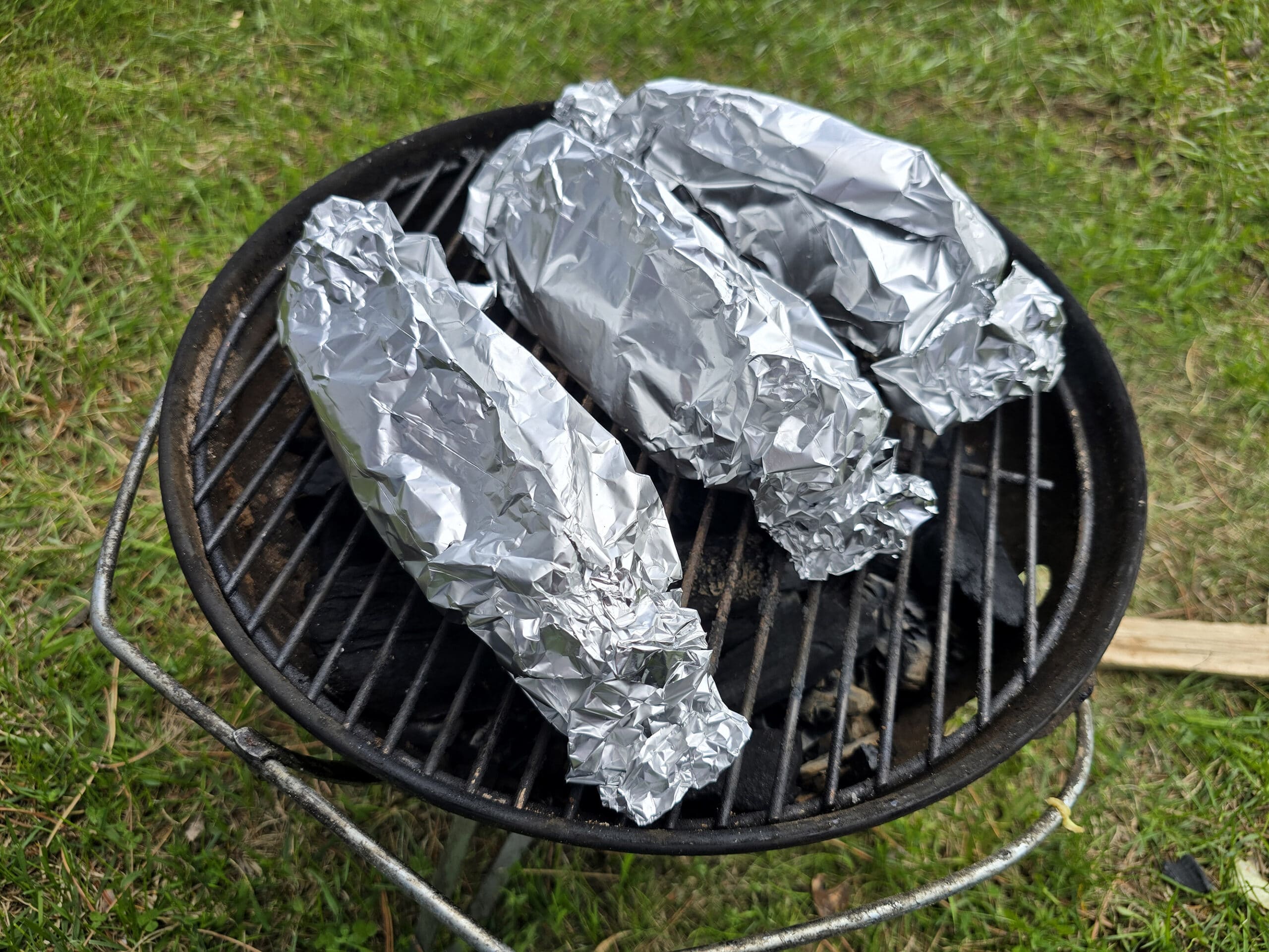 3 wrapped banana boats on a grill.