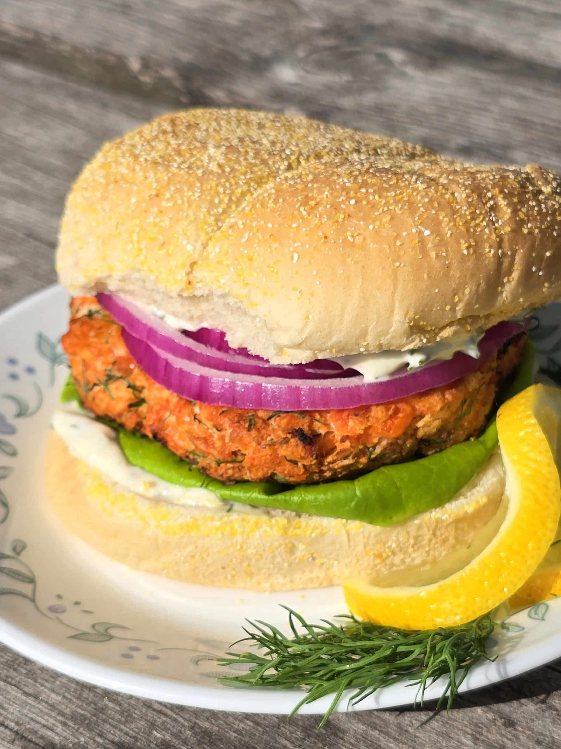 A Lemon dill fresh salmon burger with lettuce, lemon dill mayonnaise, and red onions.