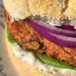 A Lemon dill salmon burger with lettuce, lemon dill mayonnaise, and red onions.