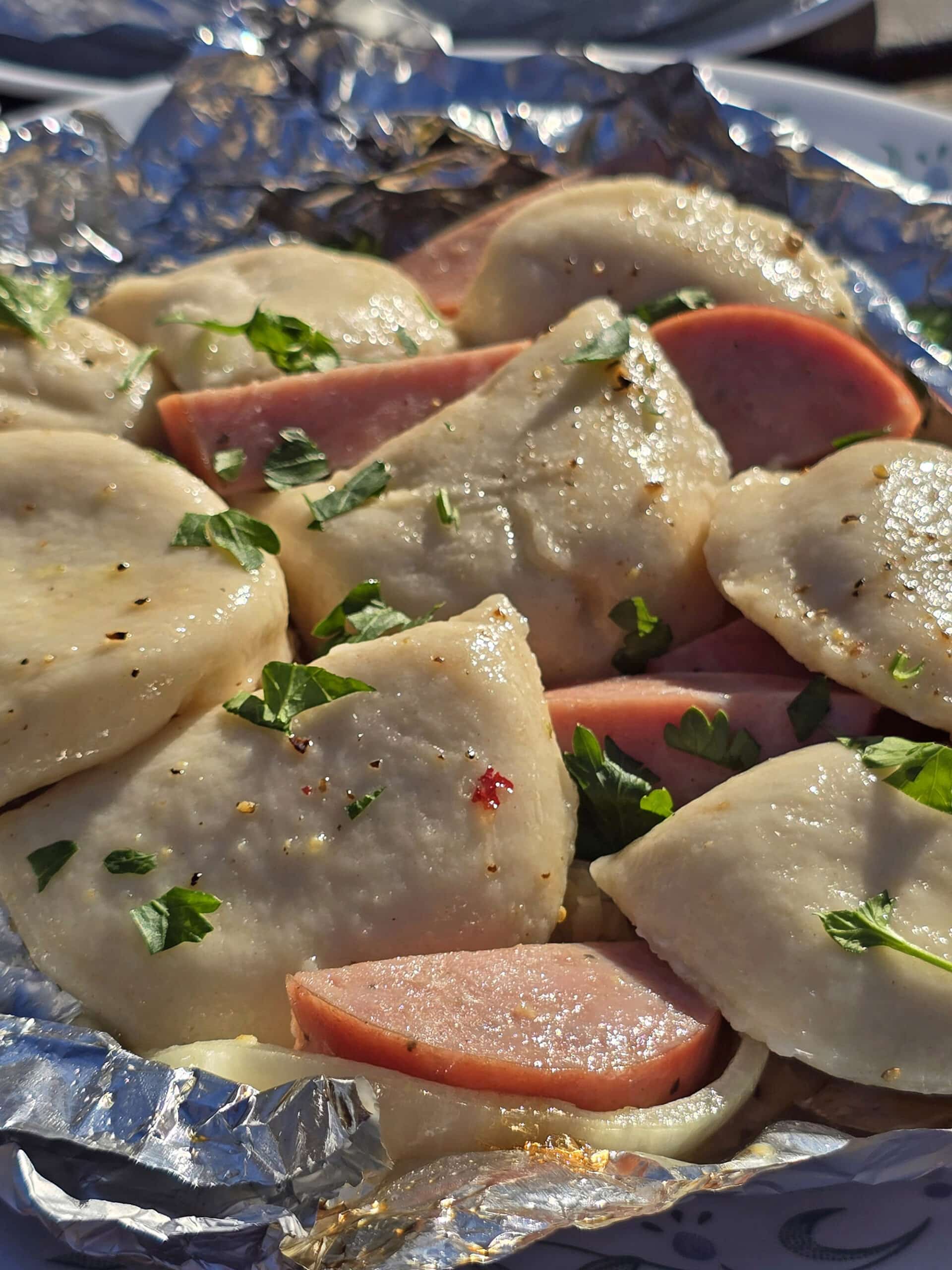 A perogies and kielbasa foil packet on a campground picnic table.