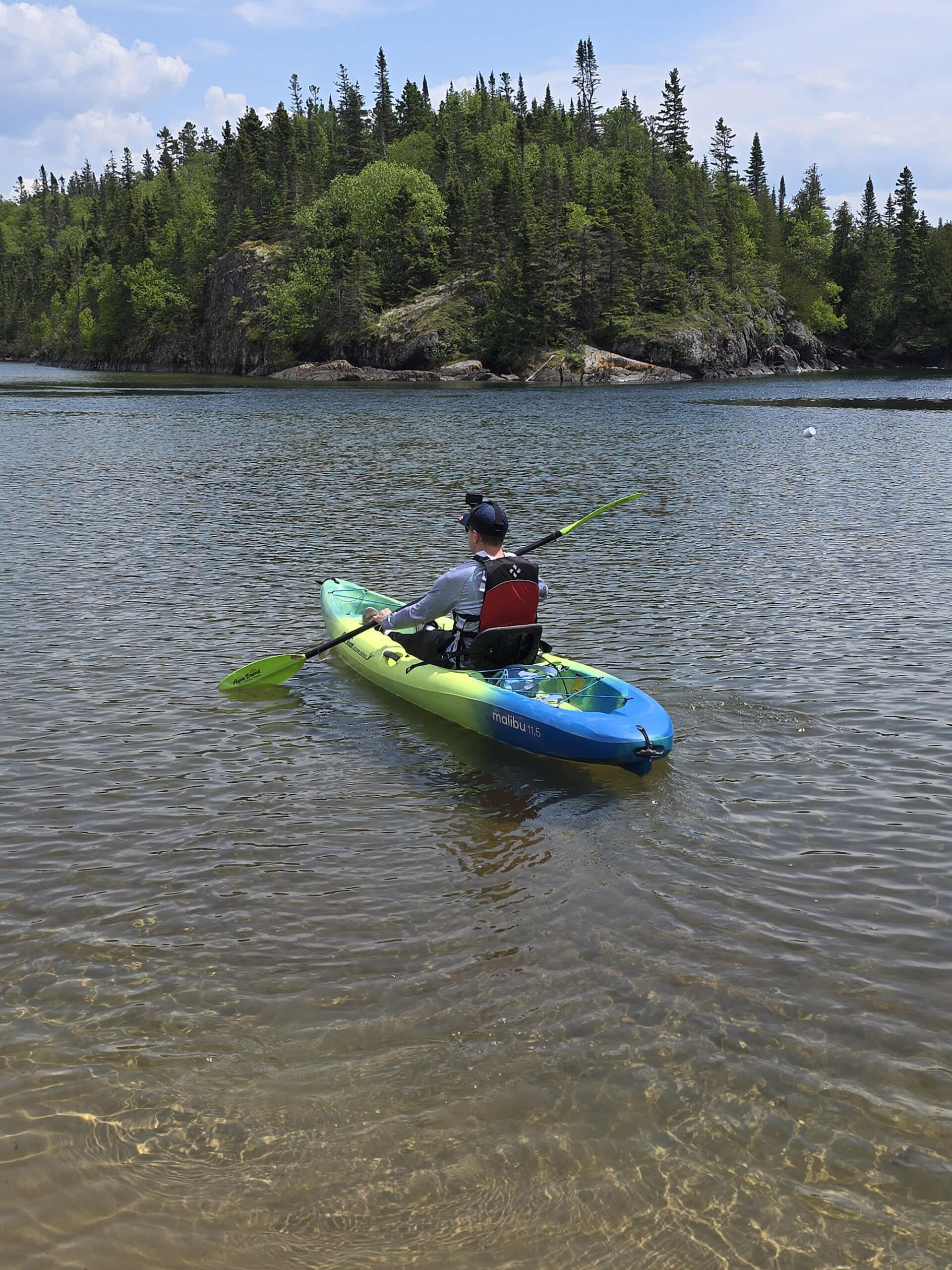 A middle ages white man in a blue and yellow kayak on Hattie’s Cove in Pukaskwa National Park.