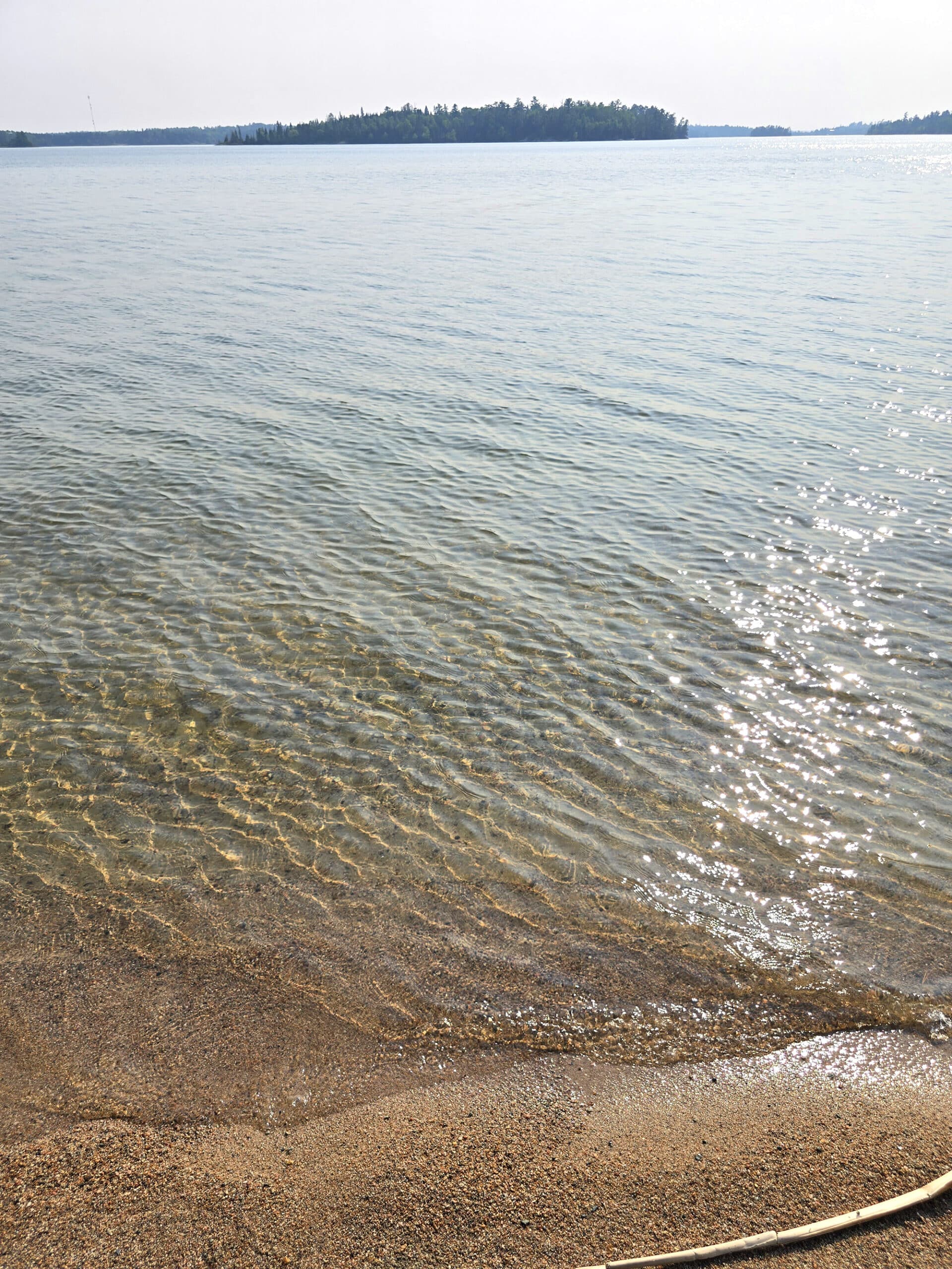 Clear lake water on a sandy beach at Sioux Narrows Provincial Park .