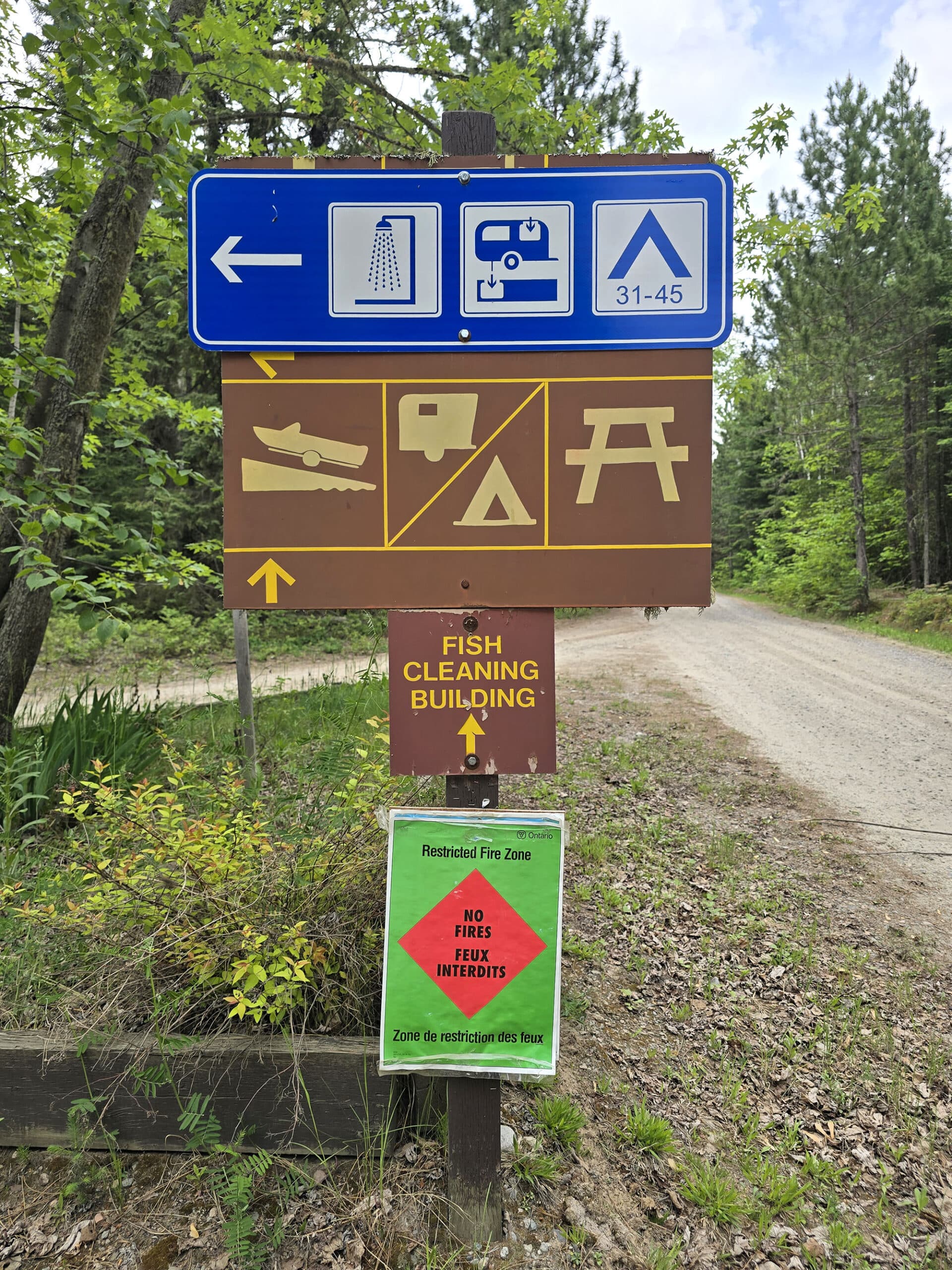 A campground sign indicating the direction to various areas of ojibway provincial park.
