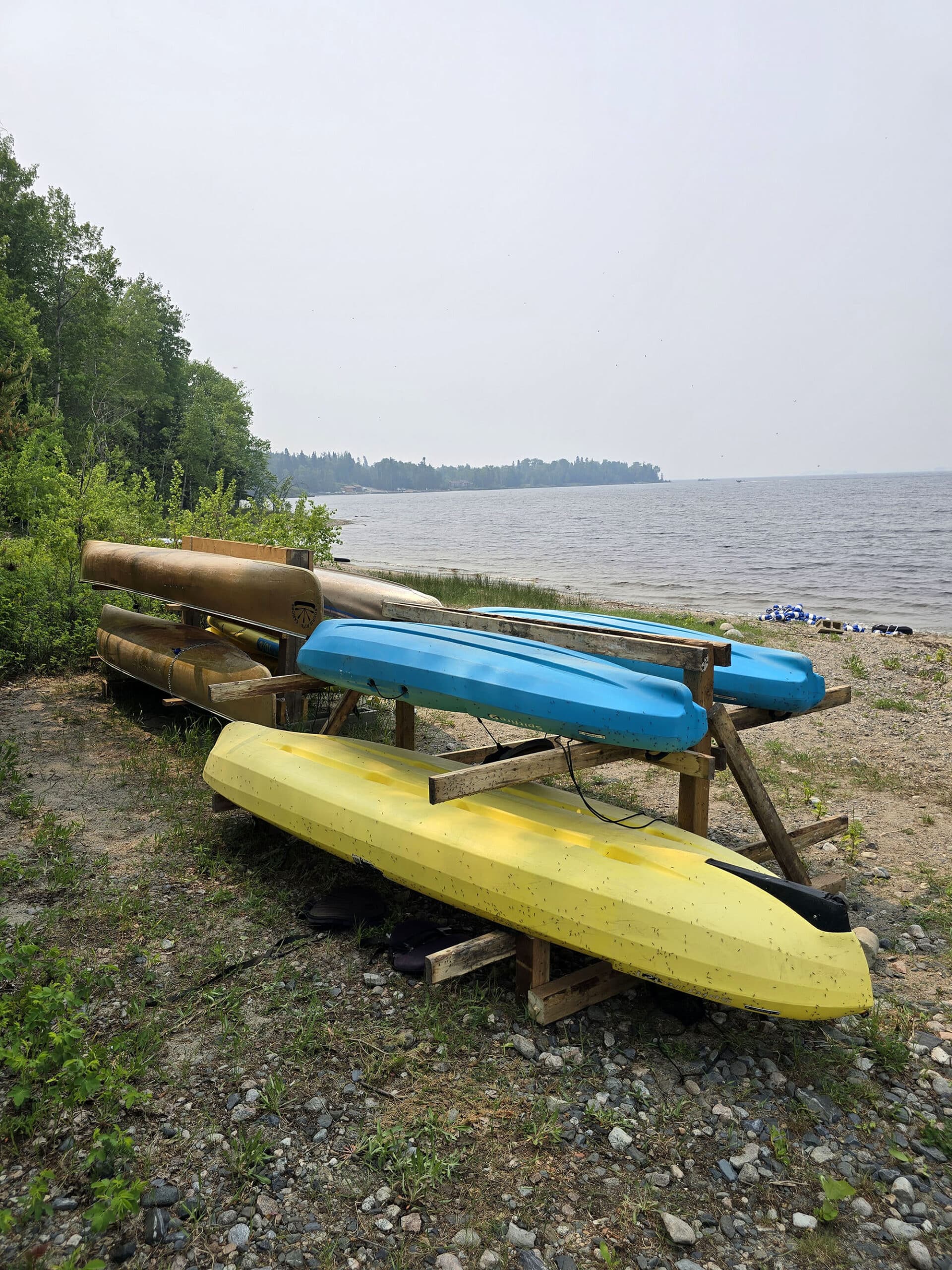 2 racks of canoes and kayaks on the side of Pakwash lake.