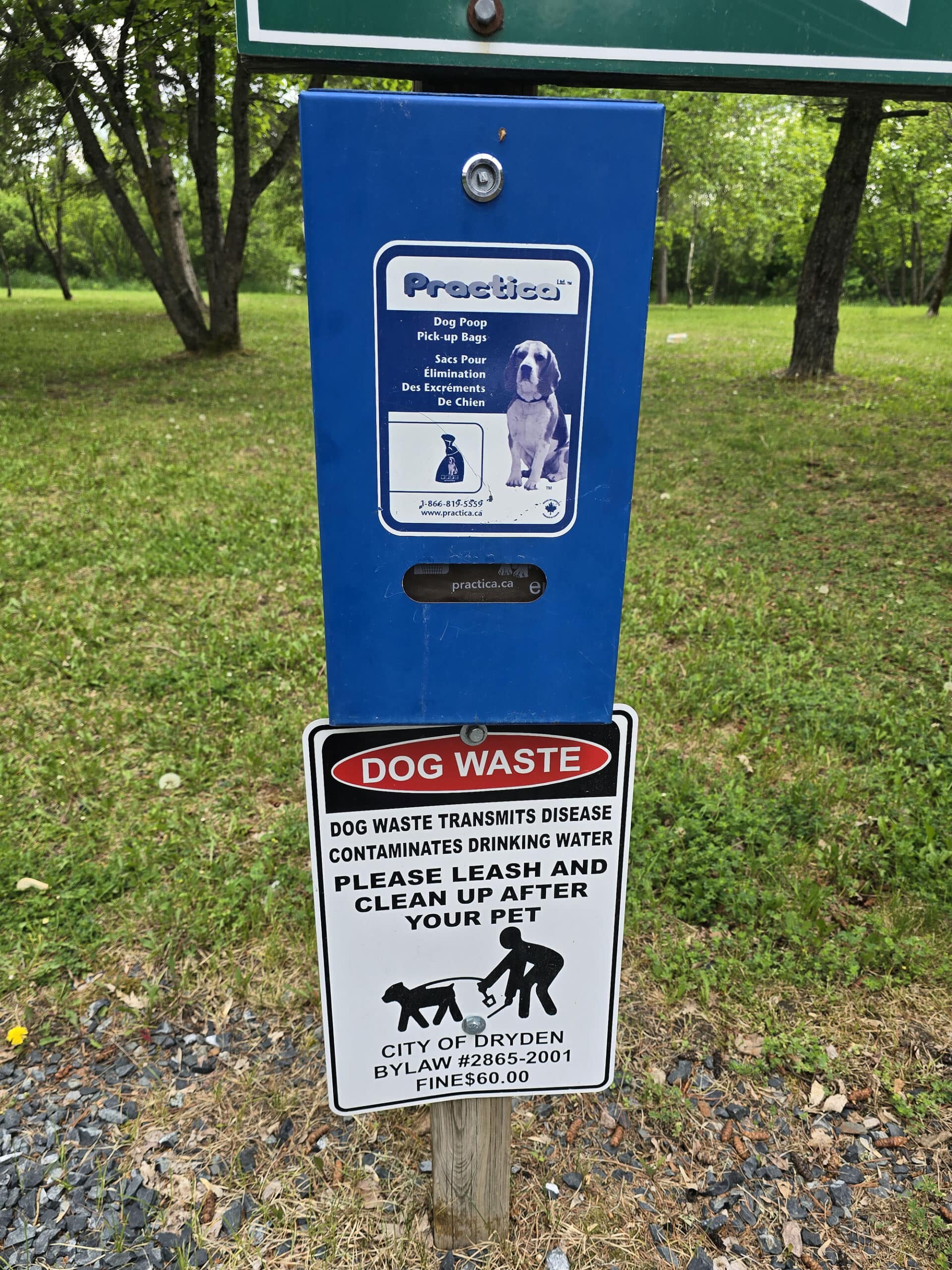 A poop bag dispenser and sign telling people to pick up after their dogs.