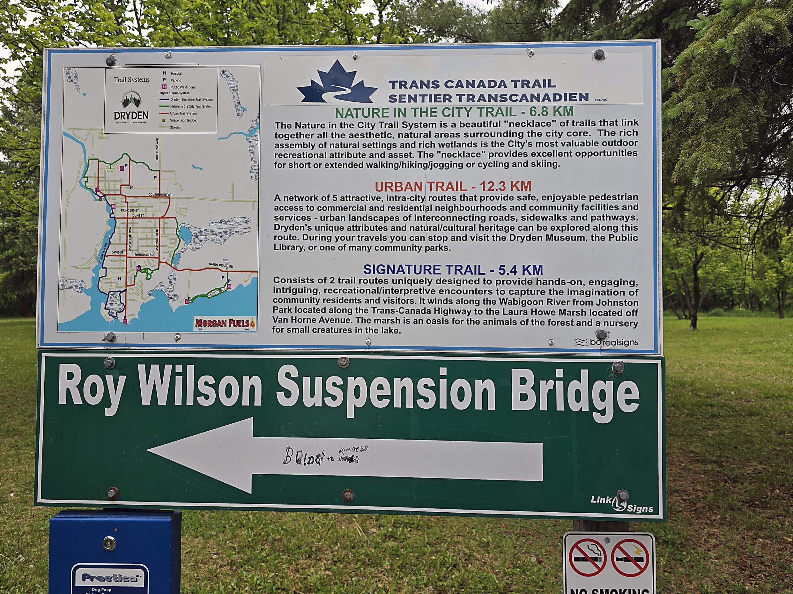 A sign pointing to the Roy Wilson Suspension Bridge and with information about the Trans Canada Trails system in Dryden Ontario.