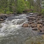 A bridge over a low cascade waterfall.