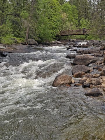 A bridge over a low cascade waterfall.