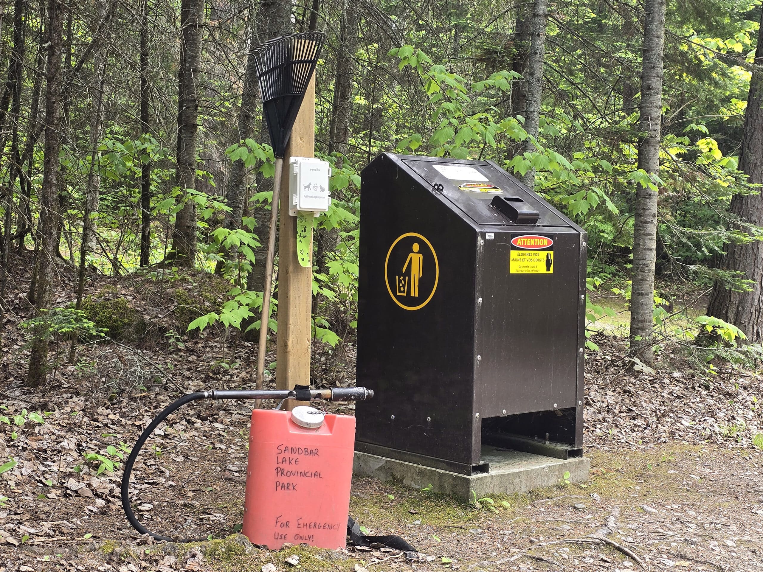 A stand with a rank and a fire suppression backpack, next to a garbage bin.