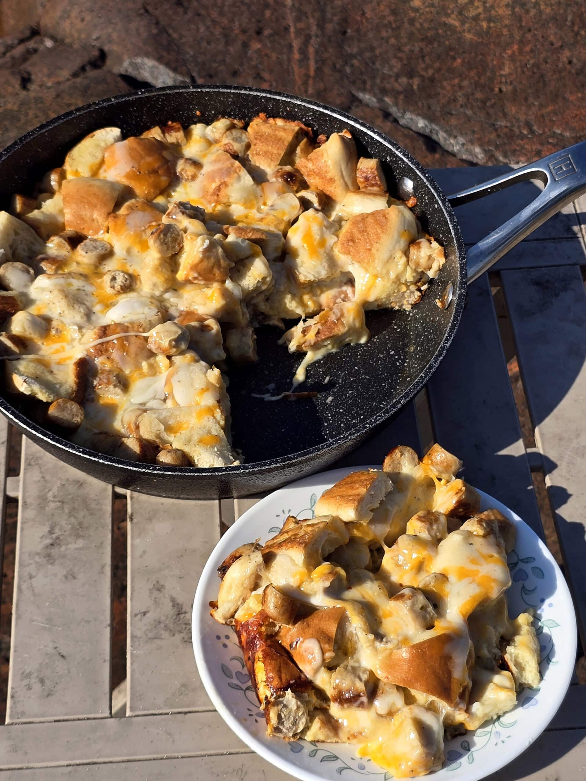 A pan and a plate of bagel breakfast casserole with sausage and cheese.