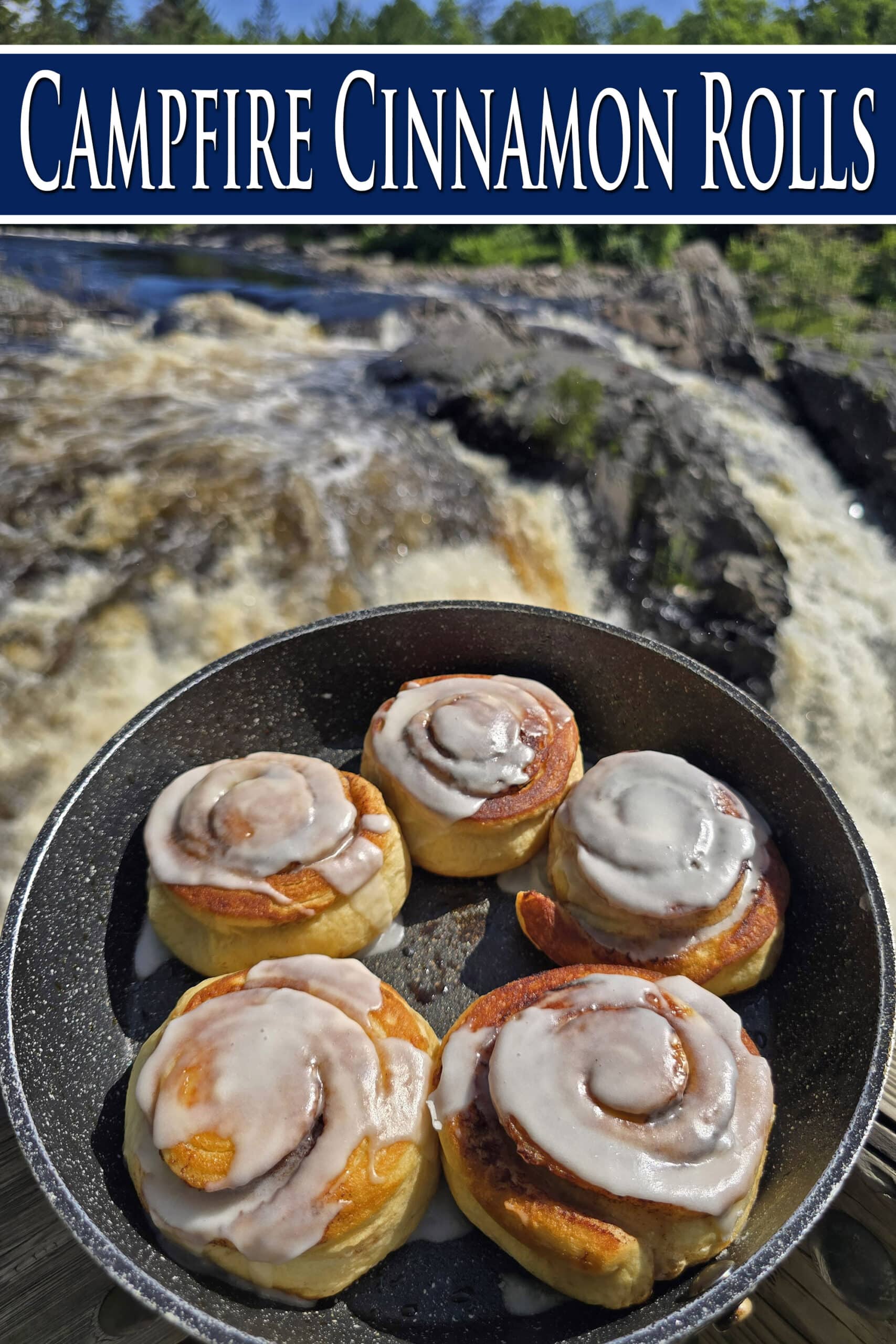 A skillet of frosted cinnamon buns next to a waterfall. Overlaid text says campfire cinnamon rolls.