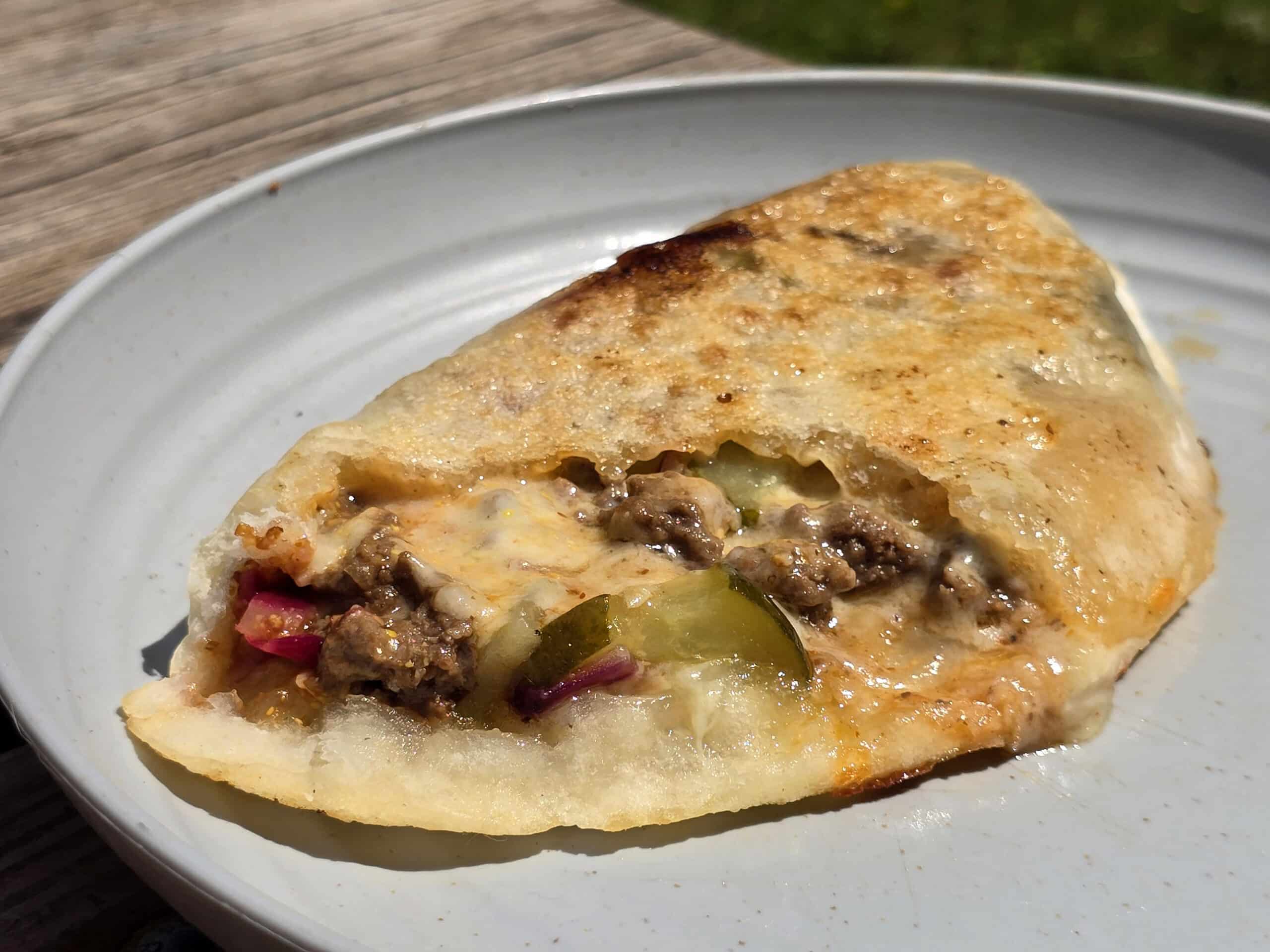 A grilled calzone stuffed with cheeseburger ingredients.