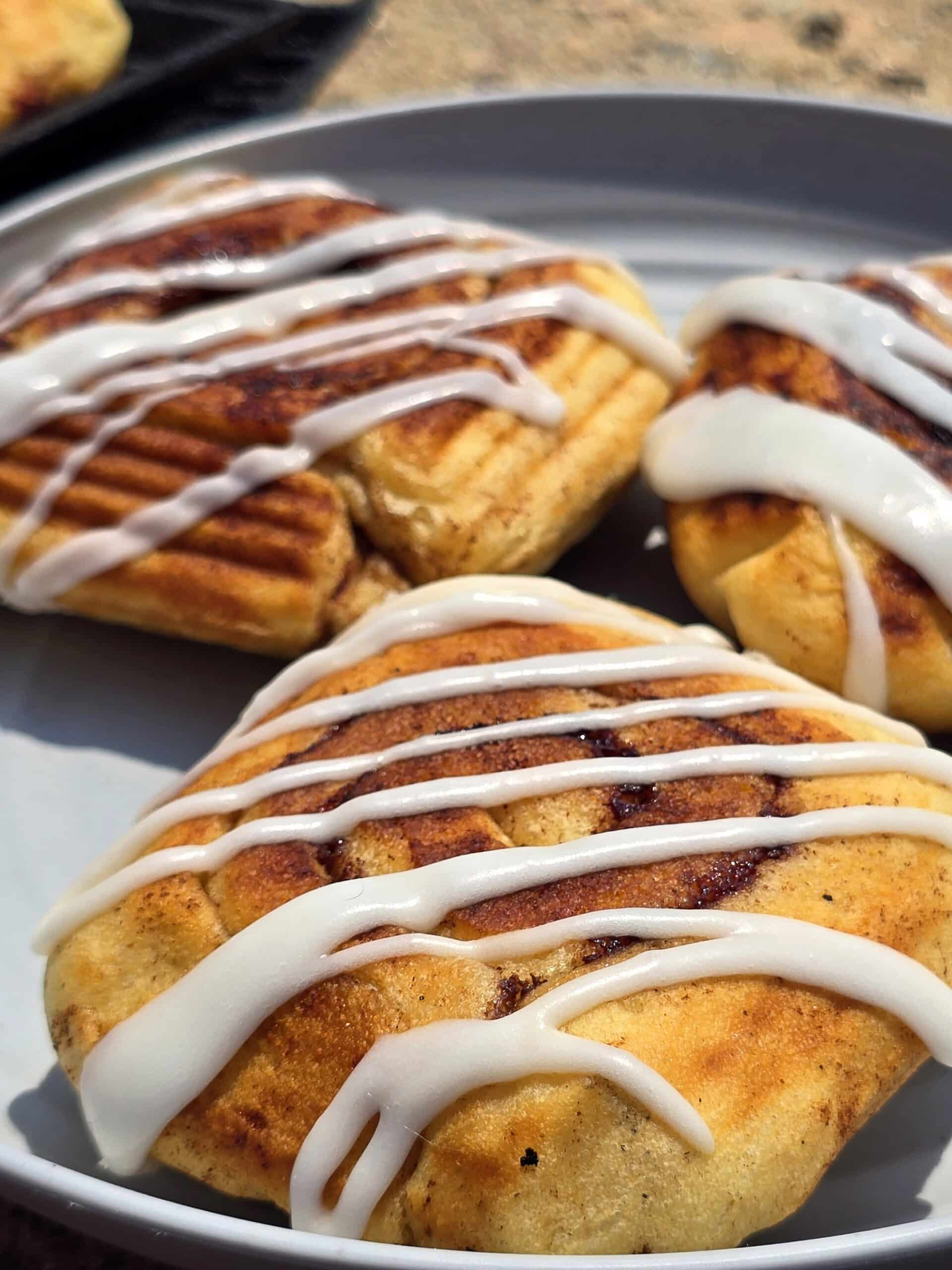 A plate of frosted pie iron cinnamon rolls.