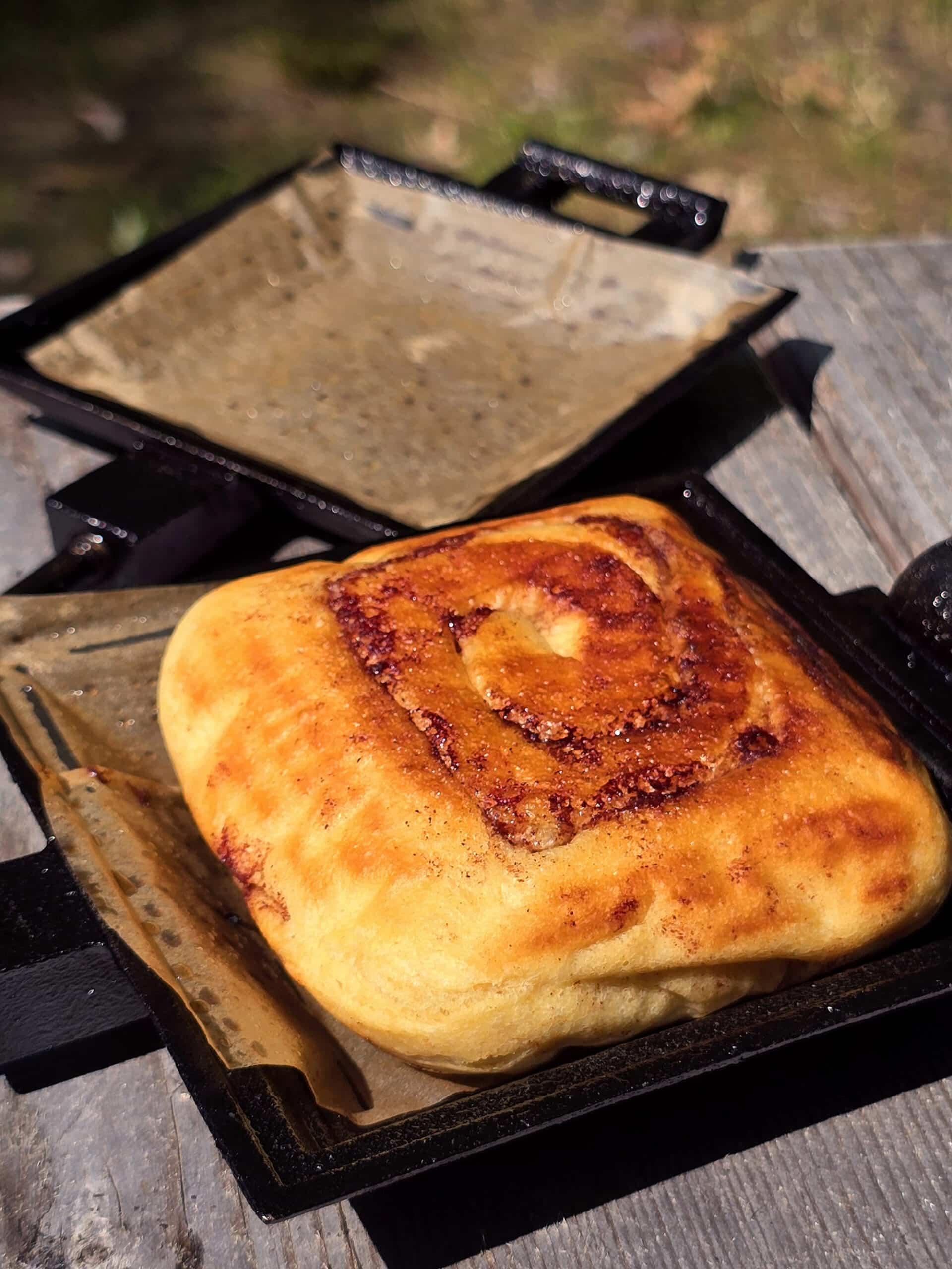 An unfrosted cinnamon bun in a pie iron.
