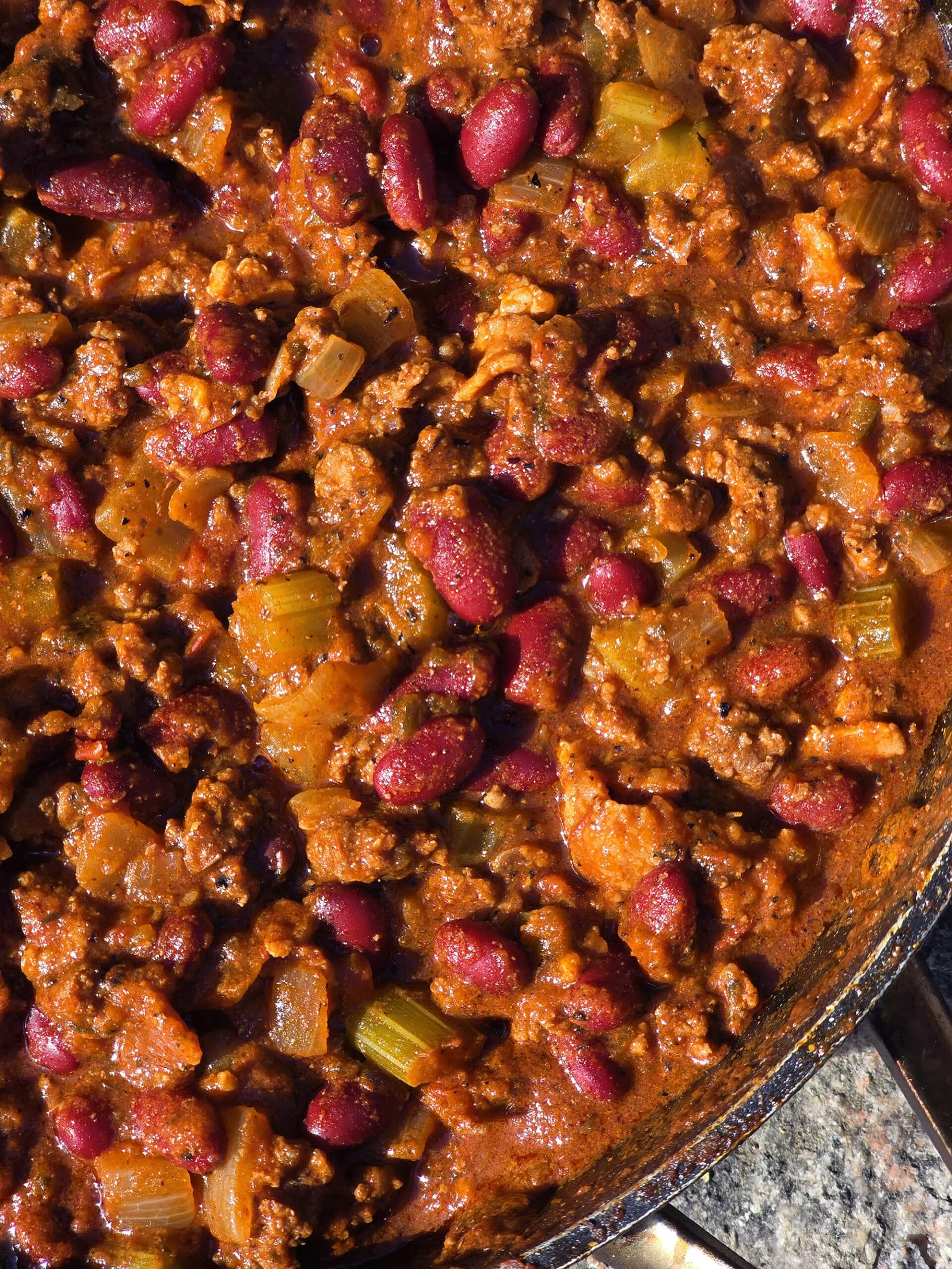 A pan of smoky venison chili with beans and chunky vegetables visible.