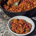 A pan and bowl of smoky venison chili with beans and chunky vegetables visible.