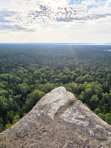 A view from the Cup and saucer trail, overlooking a cliff to the forest and distant lakes below.