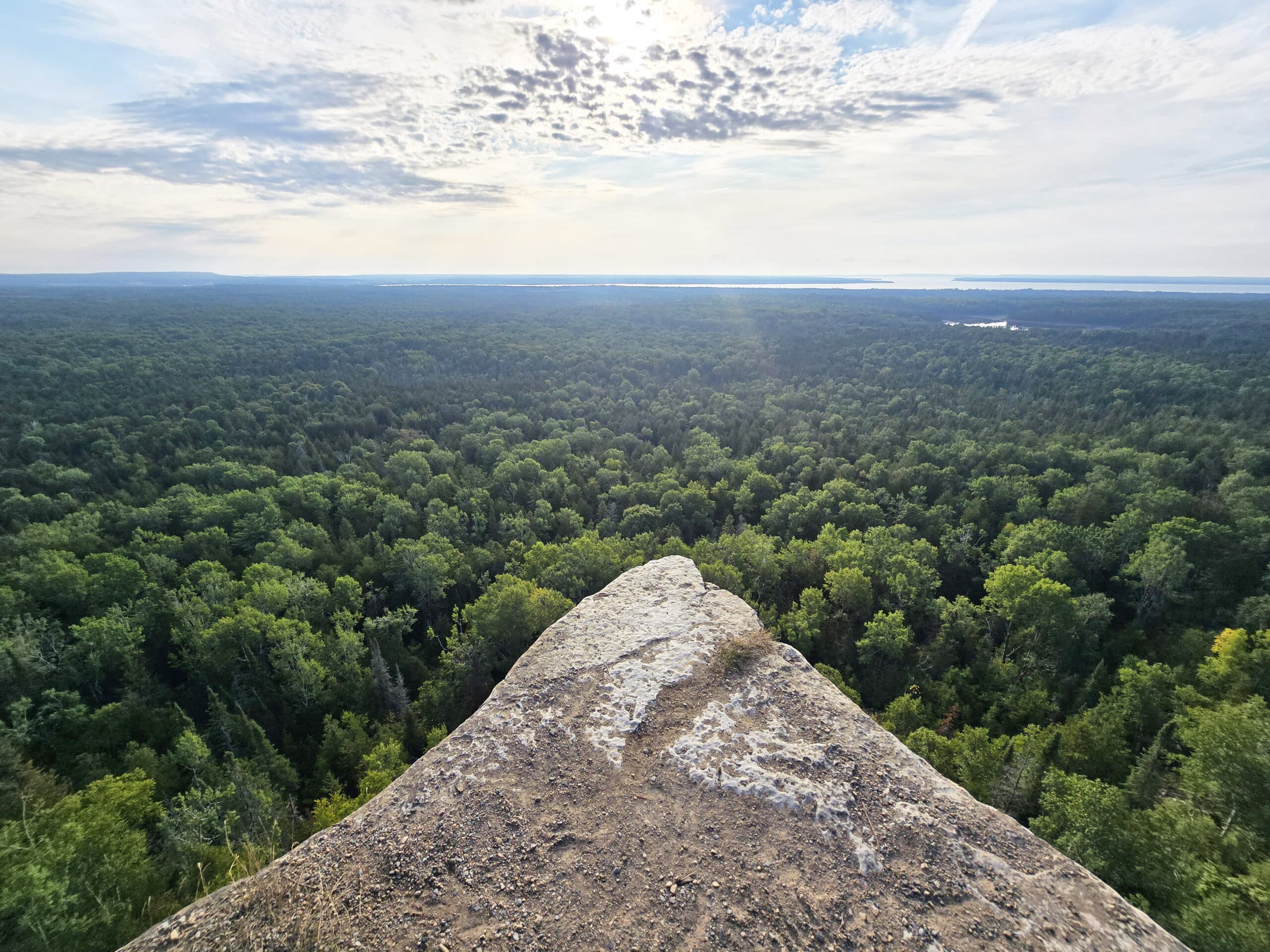 A view from the Cup and saucer trail, overlooking a cliff to the forest and distant lakes below.