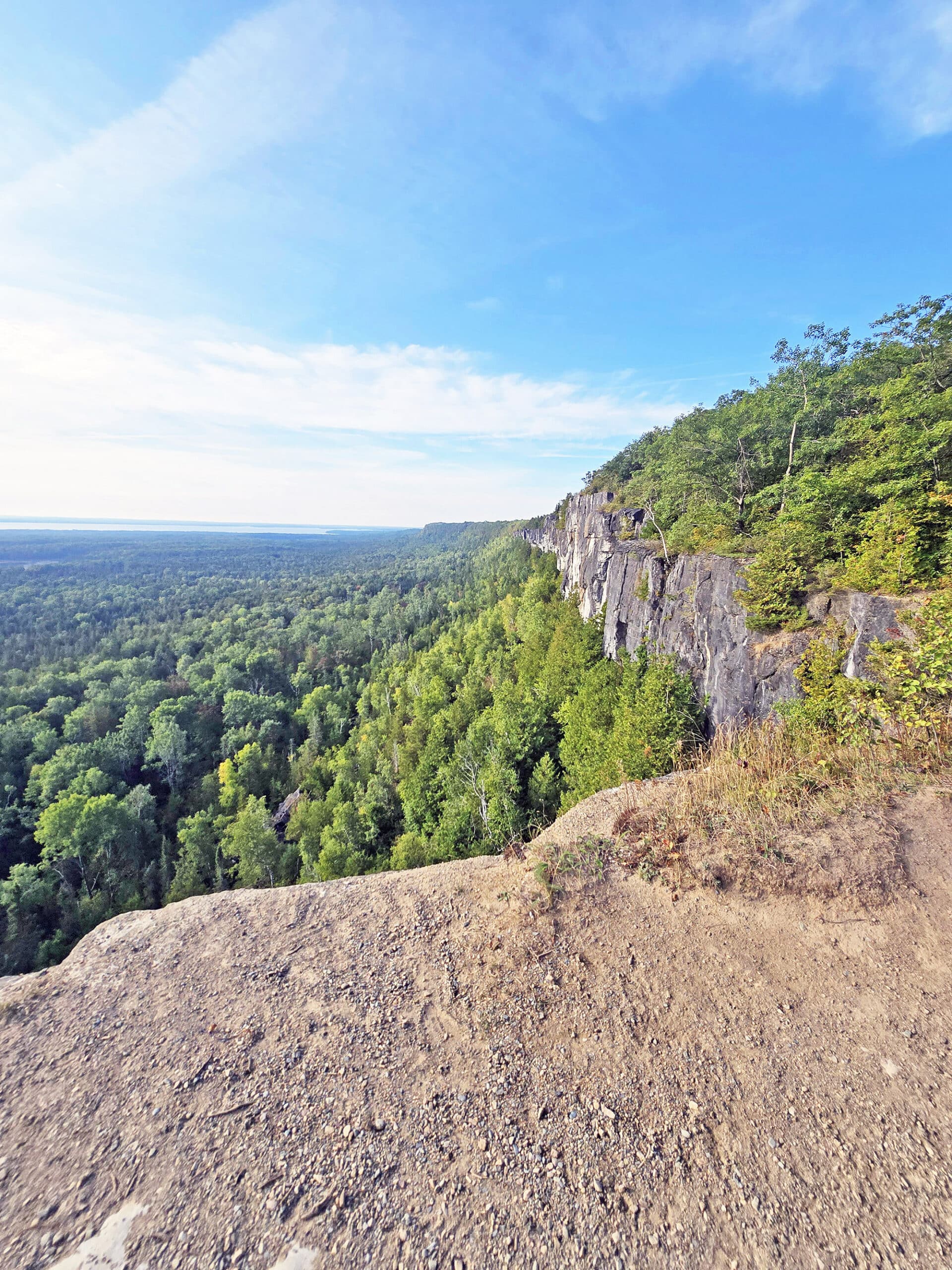 A view from the Cup and saucer trail, overlooking a cliff to the forest and distant lakes below.